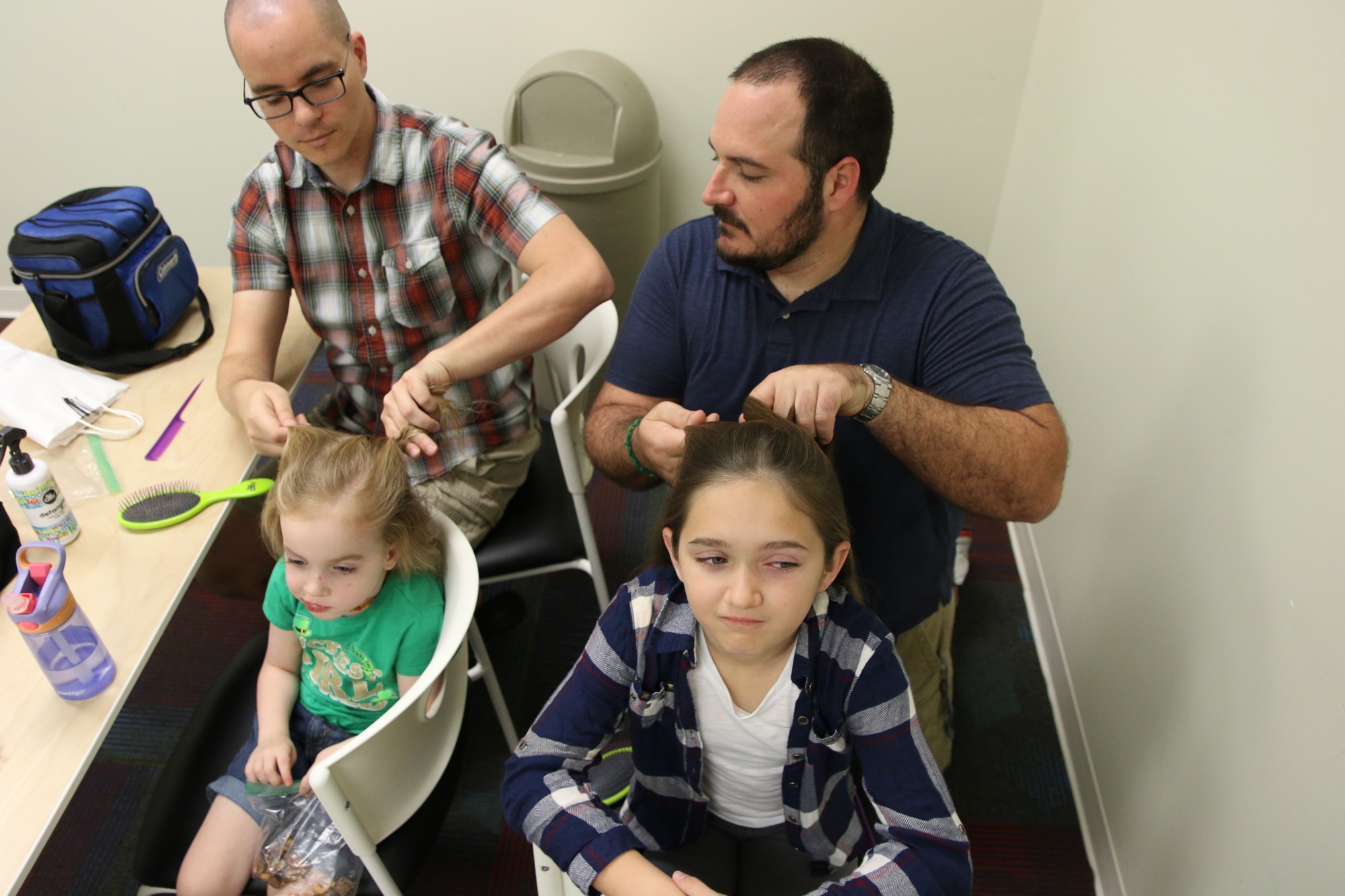 Alex Kolozvary practices braiding his daughter Charlotte Kolozvary's hair while Emma Morgese has her hair braided by her father, Philippe Morgese. Photo by Nichole Osinski
