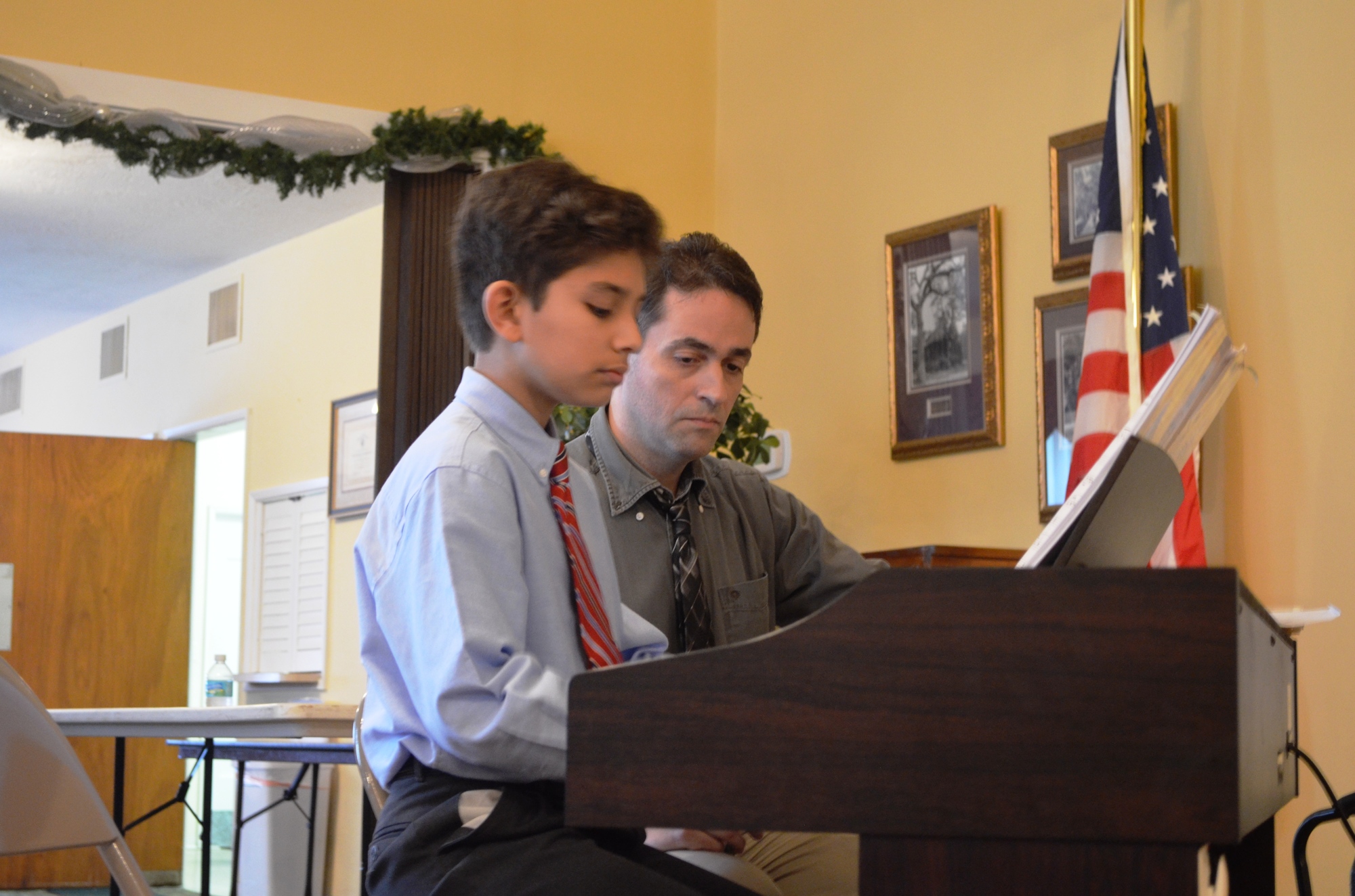 David Tafur plays piano as Damian Bonazzoli looks on.