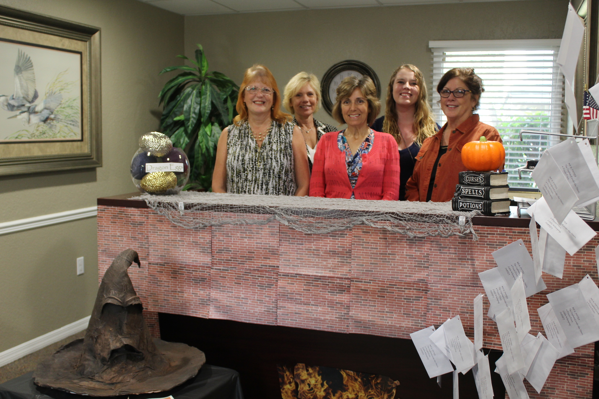 Joan Burnett, Janet Dannehower, Dulce Monahan, Krista Thompson and Elain Soriano pose behind Rager's Harry potter-themed reception desk. Not pictured are Nancy Eddy, Bev McNair, Deana Freschette and Renae Cowdell. Photo by Jarleene Almenas