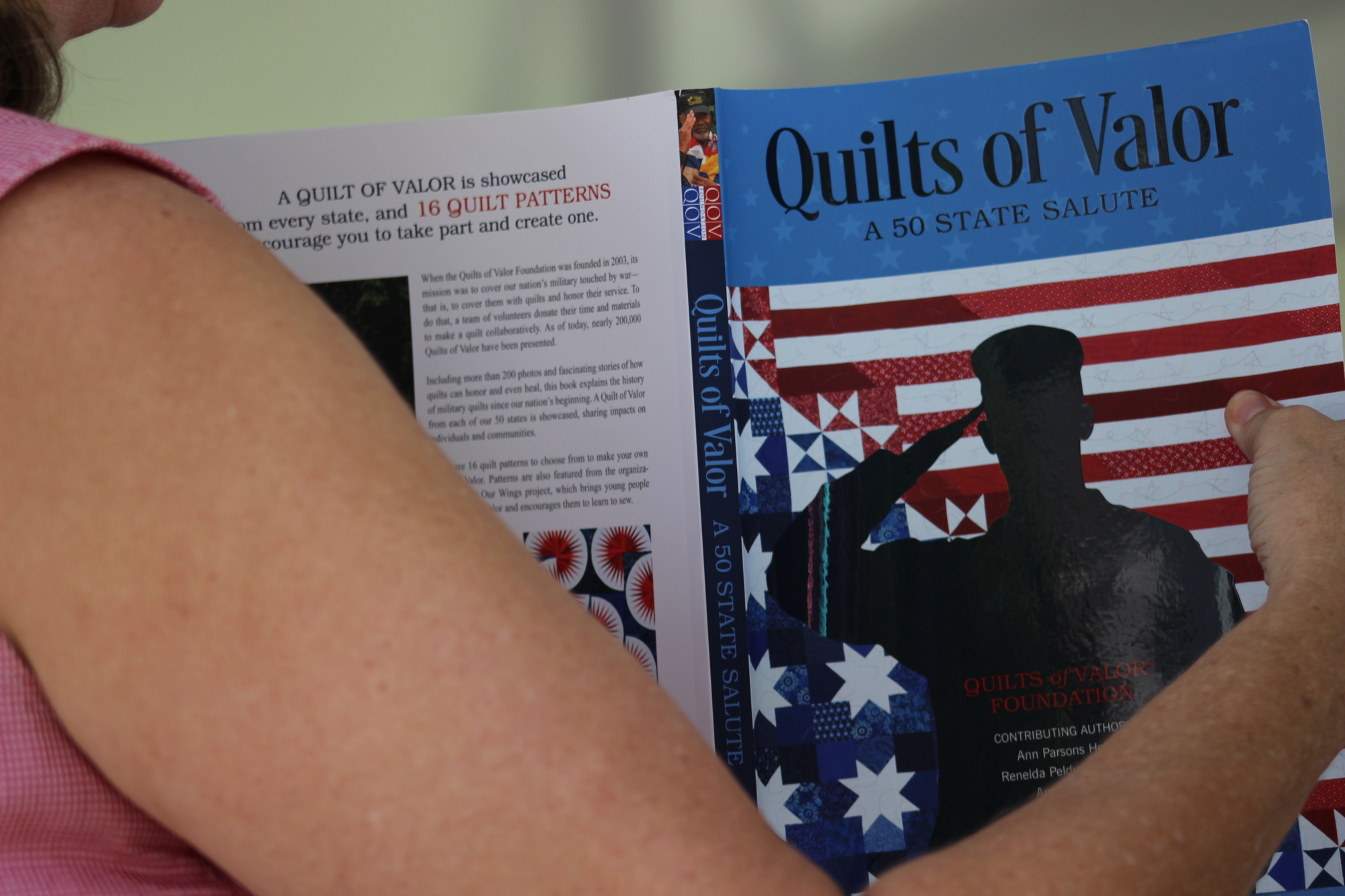 A copy of Quilts of Valor, a 50 State Salute book is held up at the first-annual QOV Golf Tournament on Saturday, March 30. Photo by Alyssa Warner