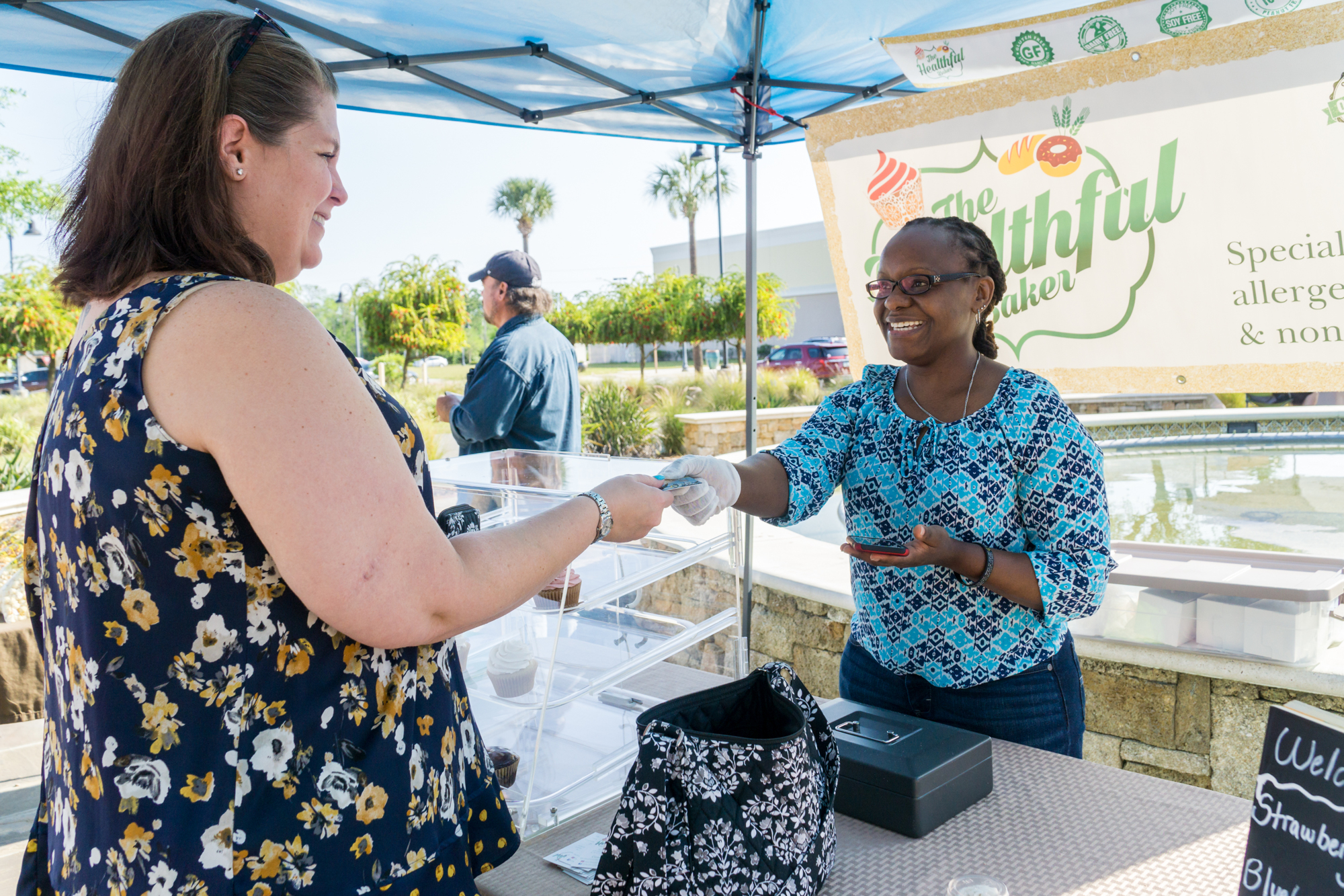 Carol Mugo serves Brenda Detweiler at the farmers market in the Pavilion in Port Orange. Photo by Zach Fedewa