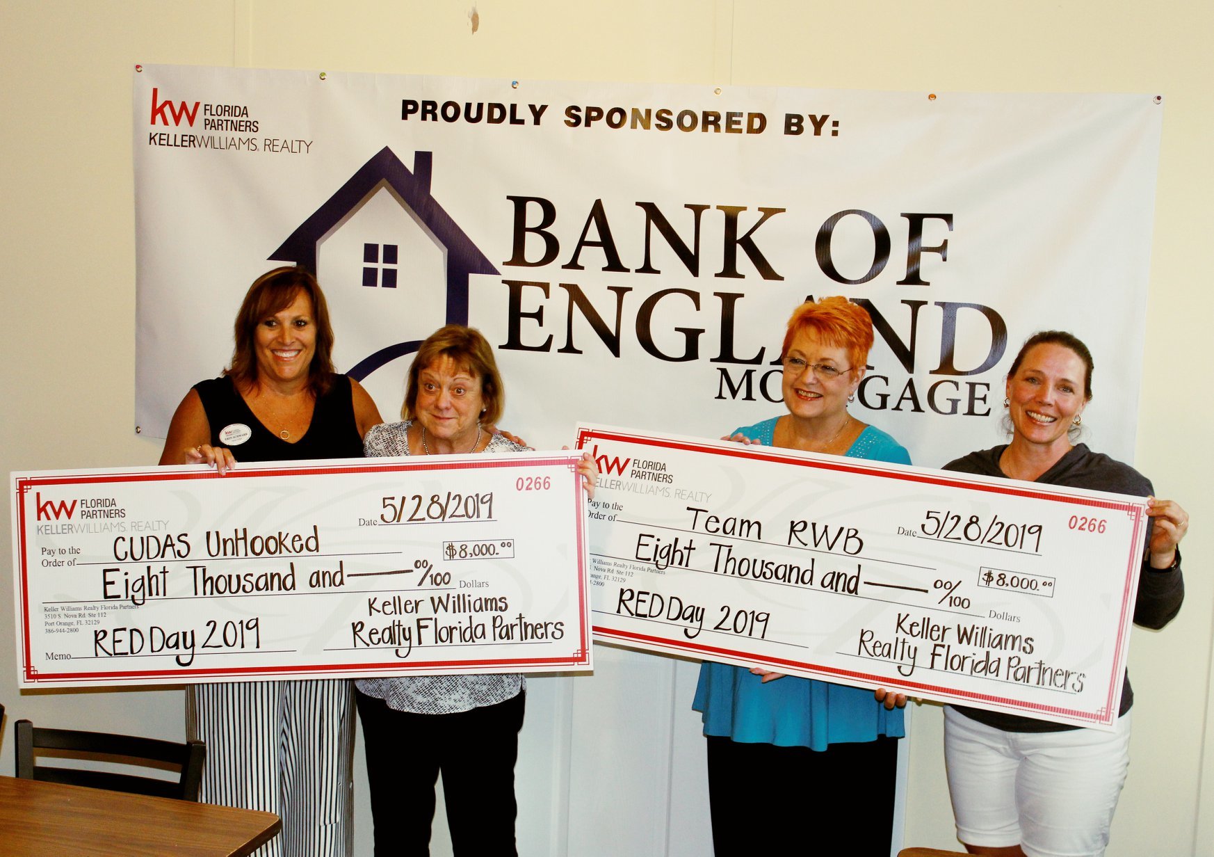 KW Realty agents Erin Schwarb and Linda Lee  awarding Team RWB Chapter Captain, Kim Bulger, and Cudas Unhooked Volunteer, Joan Norcutt, $8,000 checks raised at Red Day Appreciation Day on May 28. Photo courtesy of Erin Schwarb