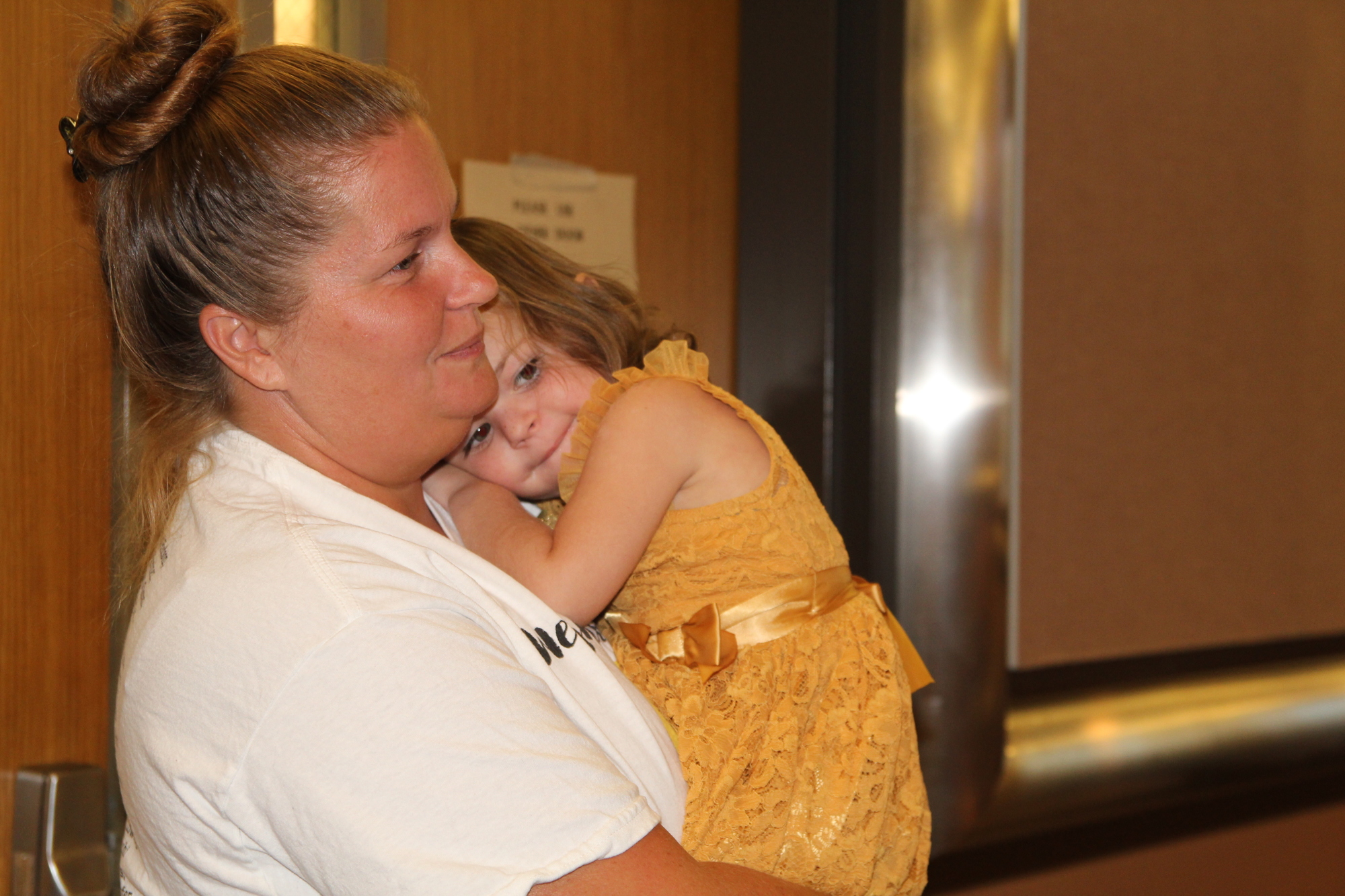 Saylor Winebrenner, 3, cuddles with her mother during the Go Gold! proclamation for childhood cancer awareness month. Photo by Tanya Russo