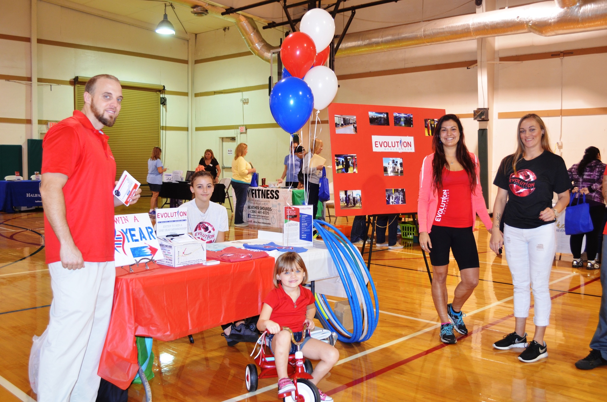 The Evolution Health Club table was colorful with balloons. Shown are Ryan Fanning, Bree Bonbistuo, Leighton Fanning (on tricycle), Jacy Figuero and Alicia Wade.