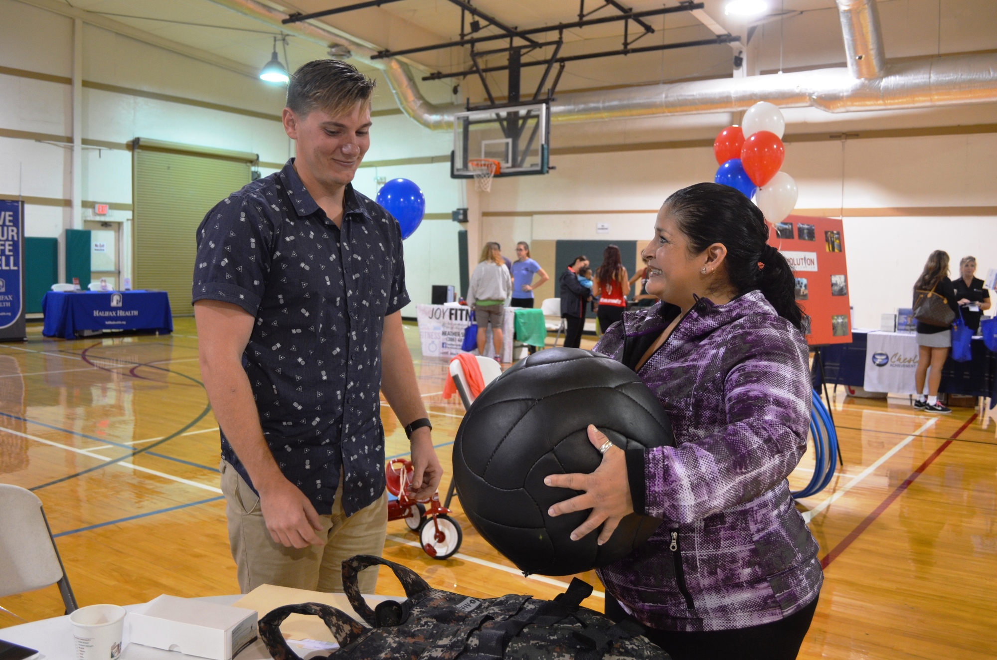 Harrison White, a personal trainer, explains the medicine ball to JoElla Macias, who signed up for the Challenge. White said getting fit means improving functional movement and living a better life.