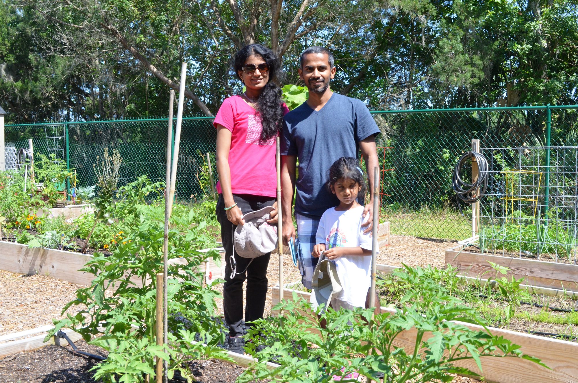 Srijesh Sridharan and Anjau Chathothu check their garden plot with daughter Nanditha Chathothu.