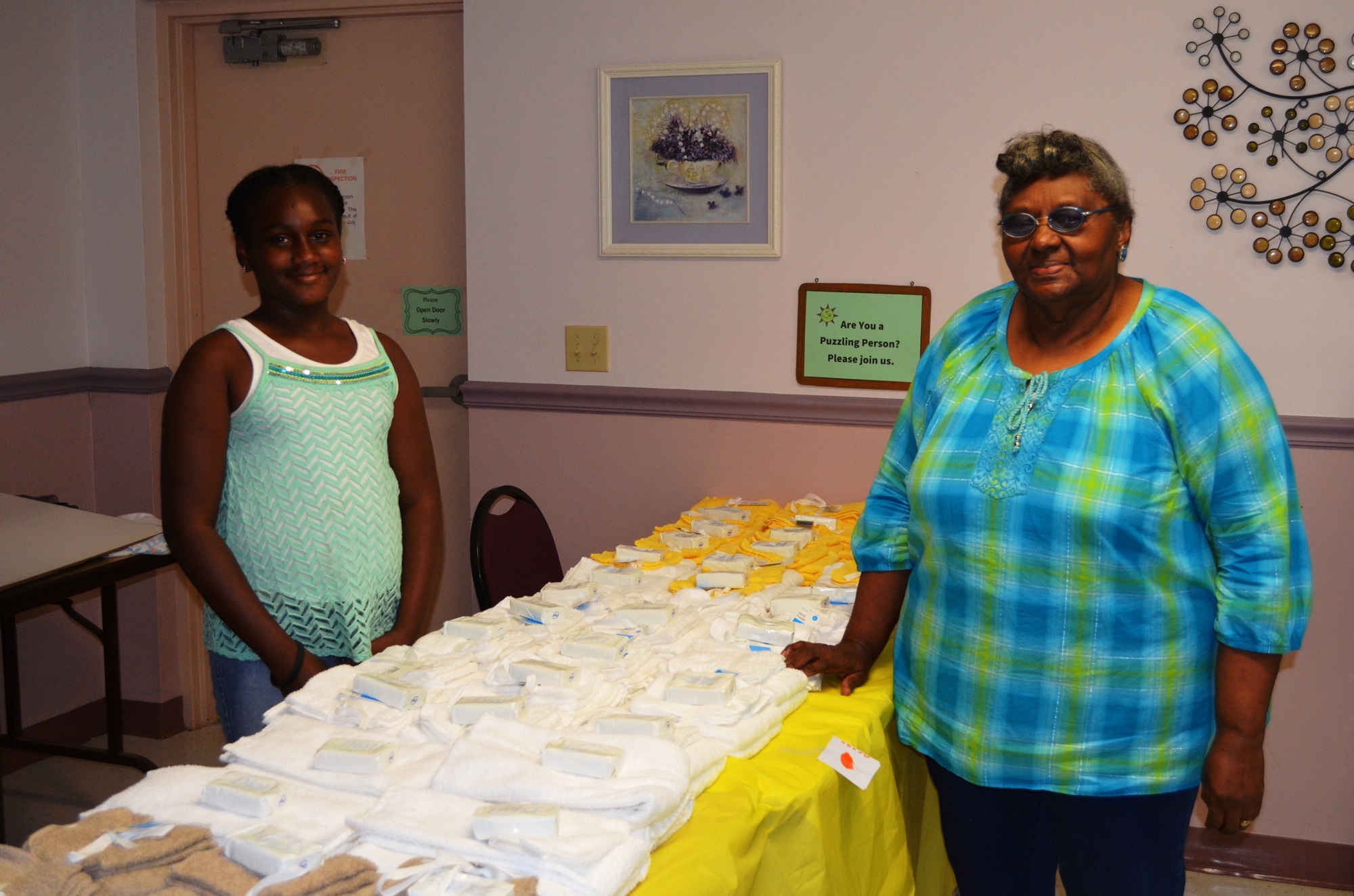 Genesis Robinson, who volunteers with her mother, Shakara, gets the bath supplies table ready with Mary Barrs, event organizer. Towels, wash cloths and soap were included. Photos by Wayne Grant