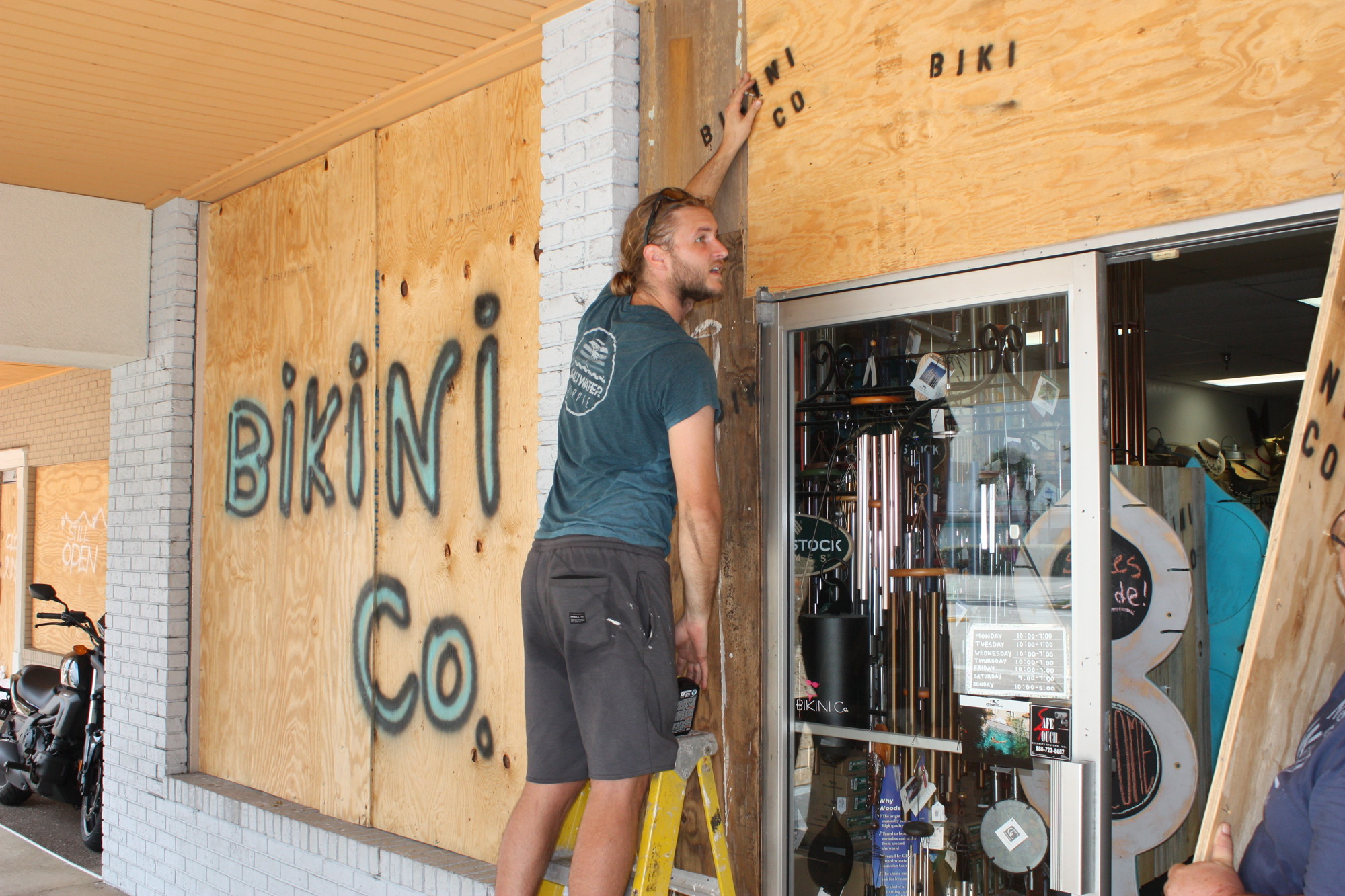 Clay Myers installs plywood on the front of The Bikini Company in Granada Plaza. Photo by Wayne Grant