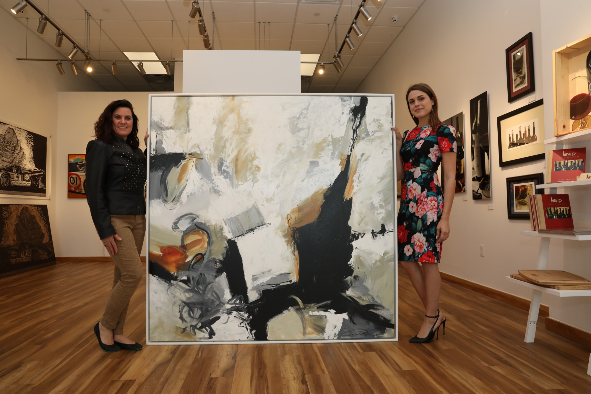 NASCAR Foundation Executive Director Nichole Krieger  and Gallery 500 Manager Jessica Kennedy show artwork purchased by Chapman Root during the “Art of Speed” exhibition. Courtesy photo