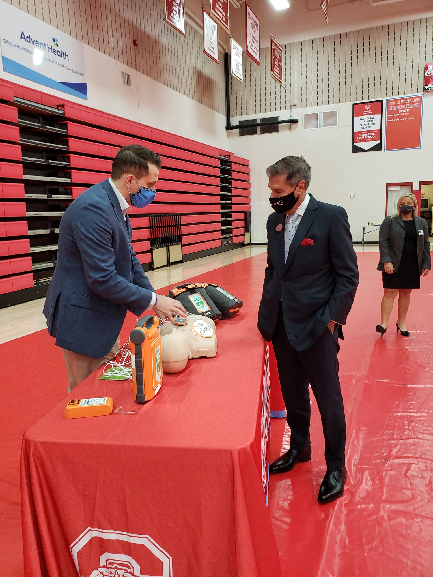 Jeff Perlow, of ZOLL Medical, demonstrates how to use the AED to School Board Member Carl Persis at the first delivery at Seabreeze High School. Courtesy photo
