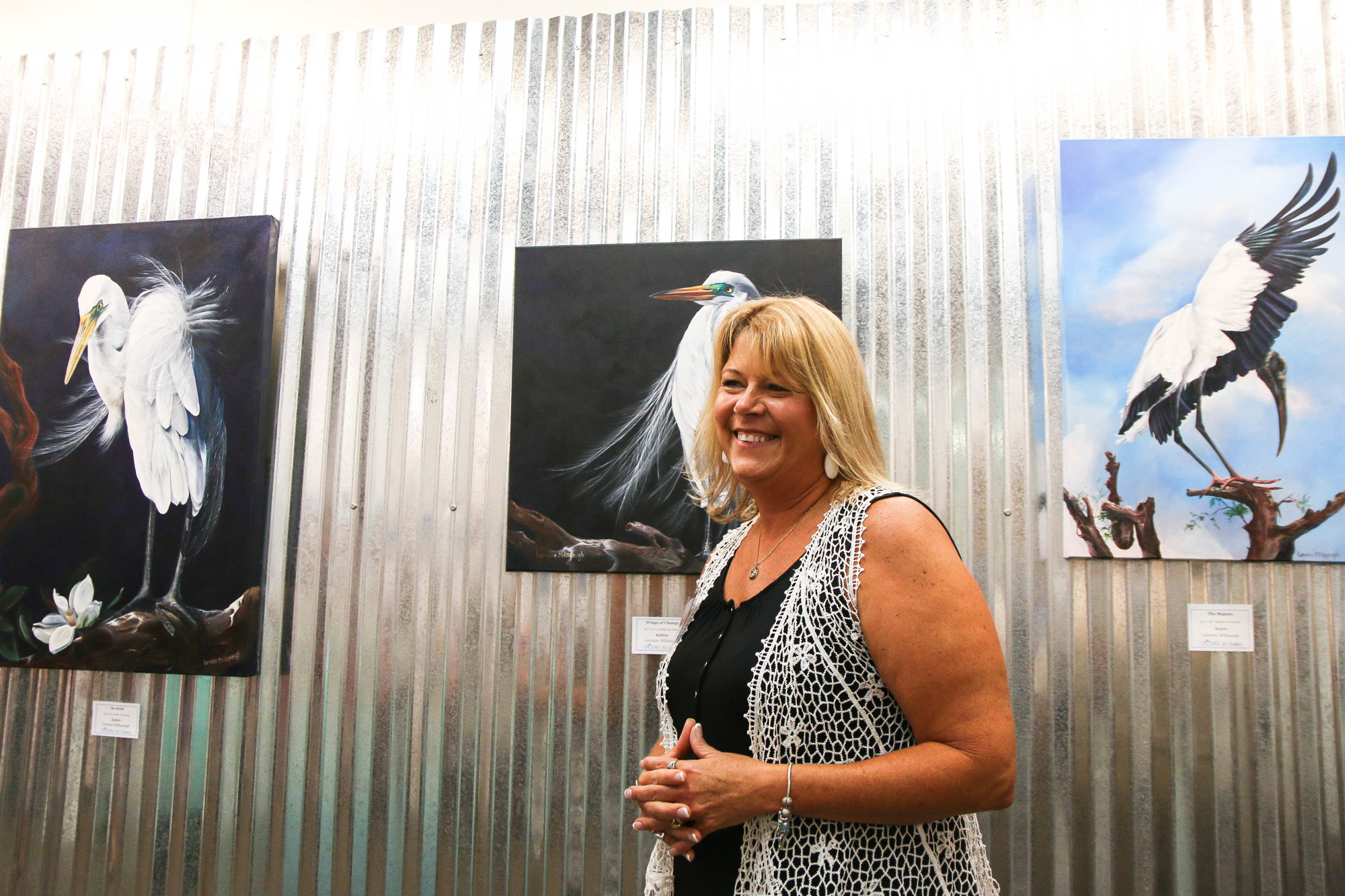 Artist Lorraine Millspaugh smiles in front of her exhibit, 