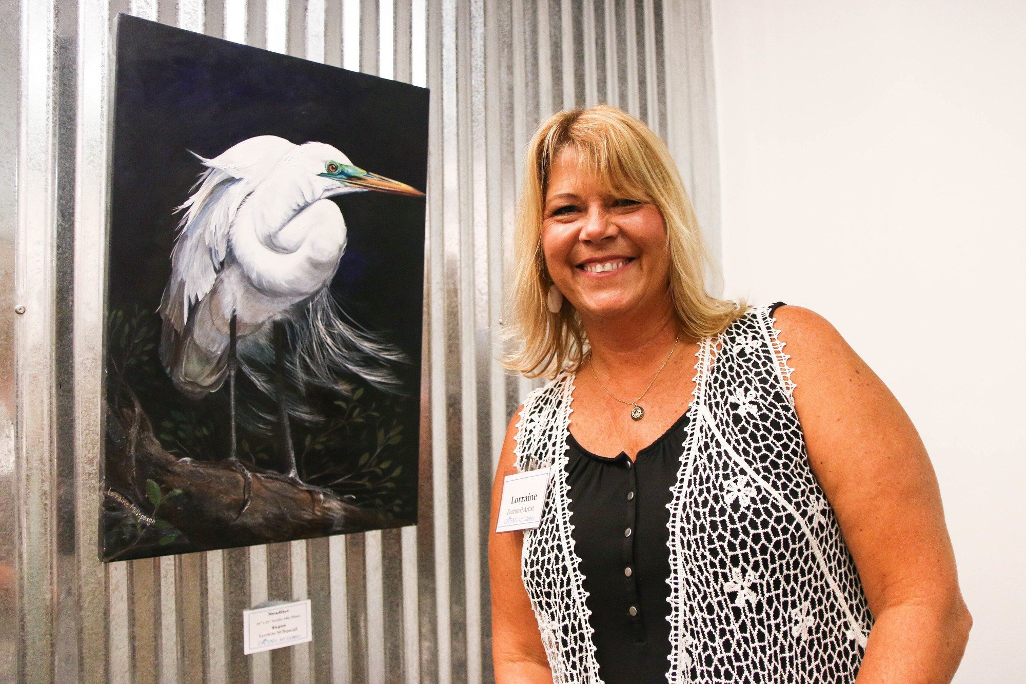 Artist Lorraine Millspaugh poses in front of her favorite painting, titled 