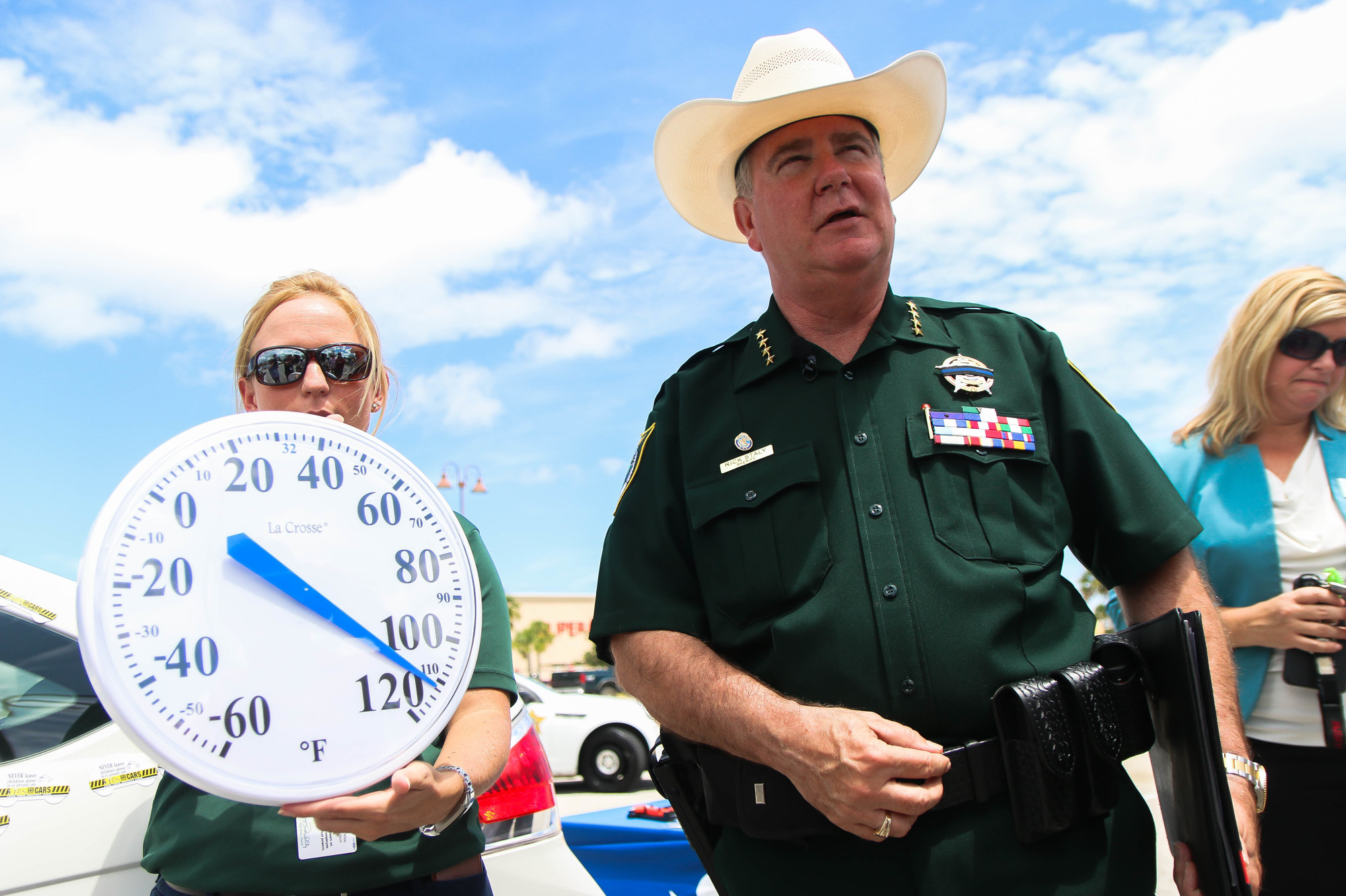 While Sheriff Rick Staly speaks to the media, FSCO PIO Brittany Kershaw holds up the temperature of the car's interior after about 19 minutes of being turned off. Photo by Paige Wilson