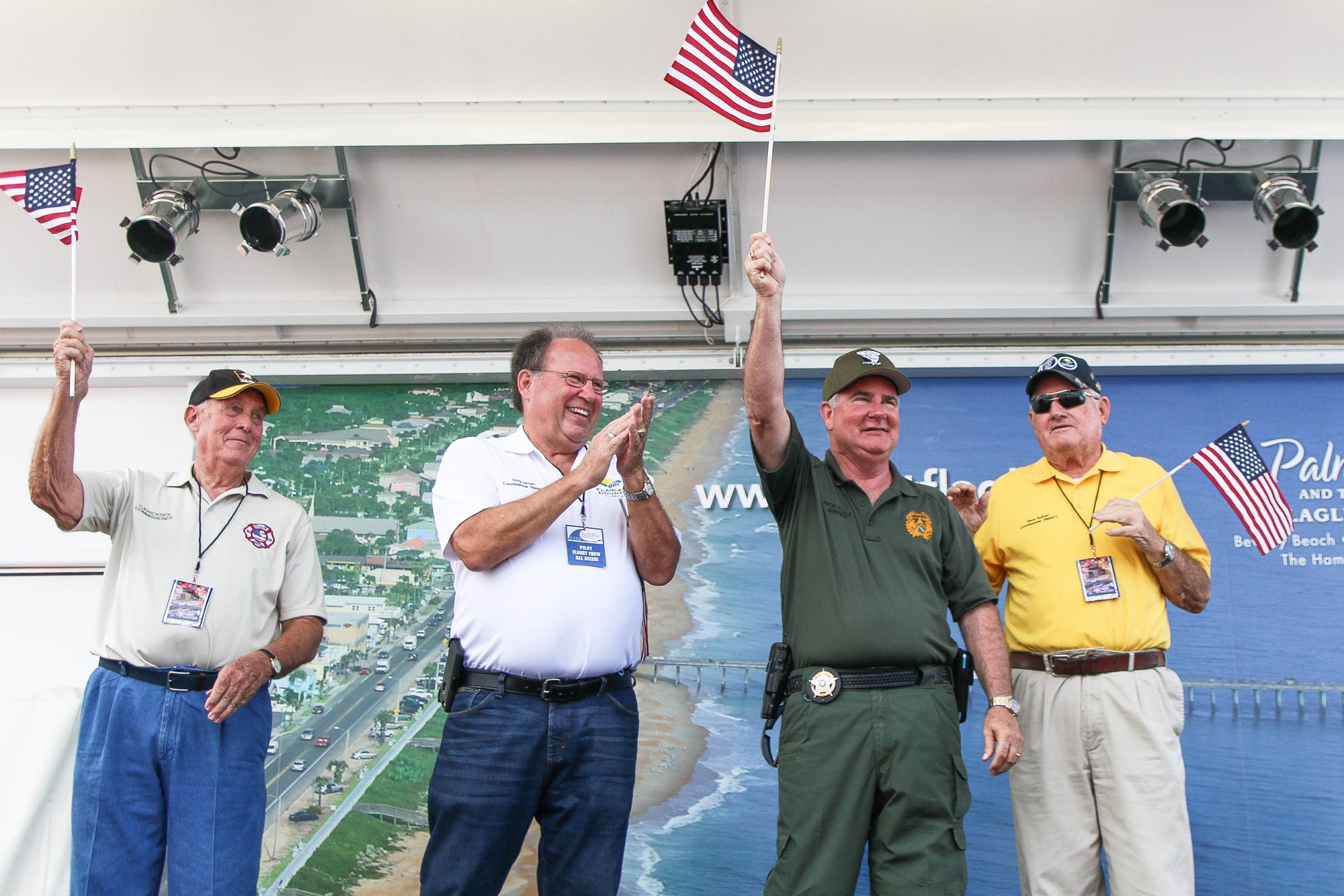 Flagler County Sheriff Rick Staly waves his flag high, as he stands next to Flagler County Commissioners Charles Ericksen Jr., Gregory Hansen and David Sullivan. Photo by Paige Wilson