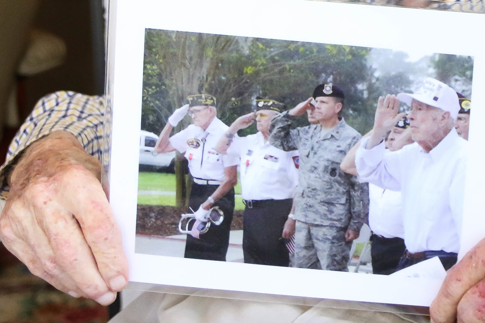 Frank Hedrick holds up a photo of him at a Veterans Day ceremony from about three years ago. Photo by Paige Wilson