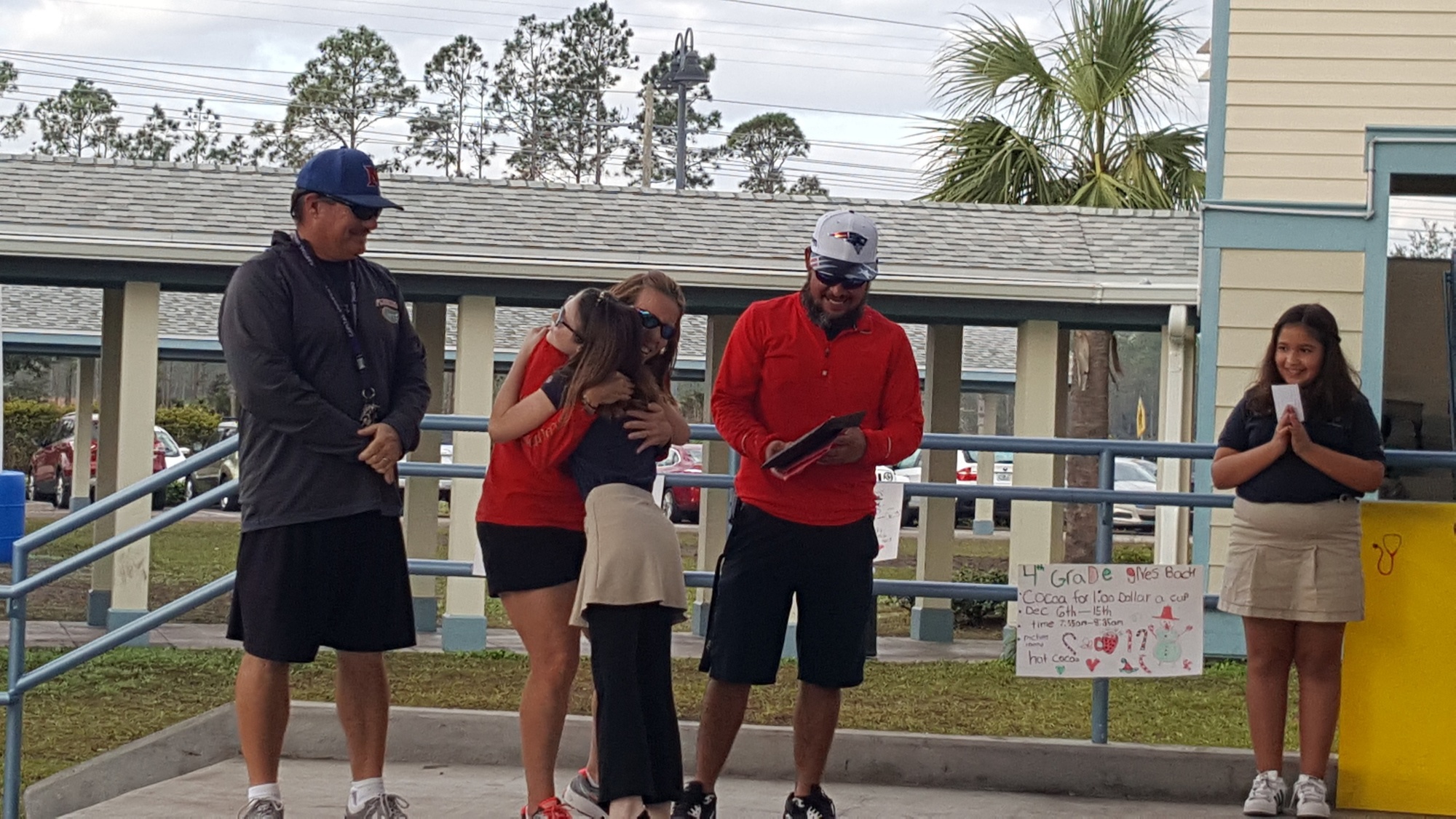 PE Coaches Bob McVey and Terry Baker stand by as student Mary Frances Blunk hugs Coach Marie Stephenson after students raised money for a permanent basketball hoop for PE. Courtesy photo by Sam Allen