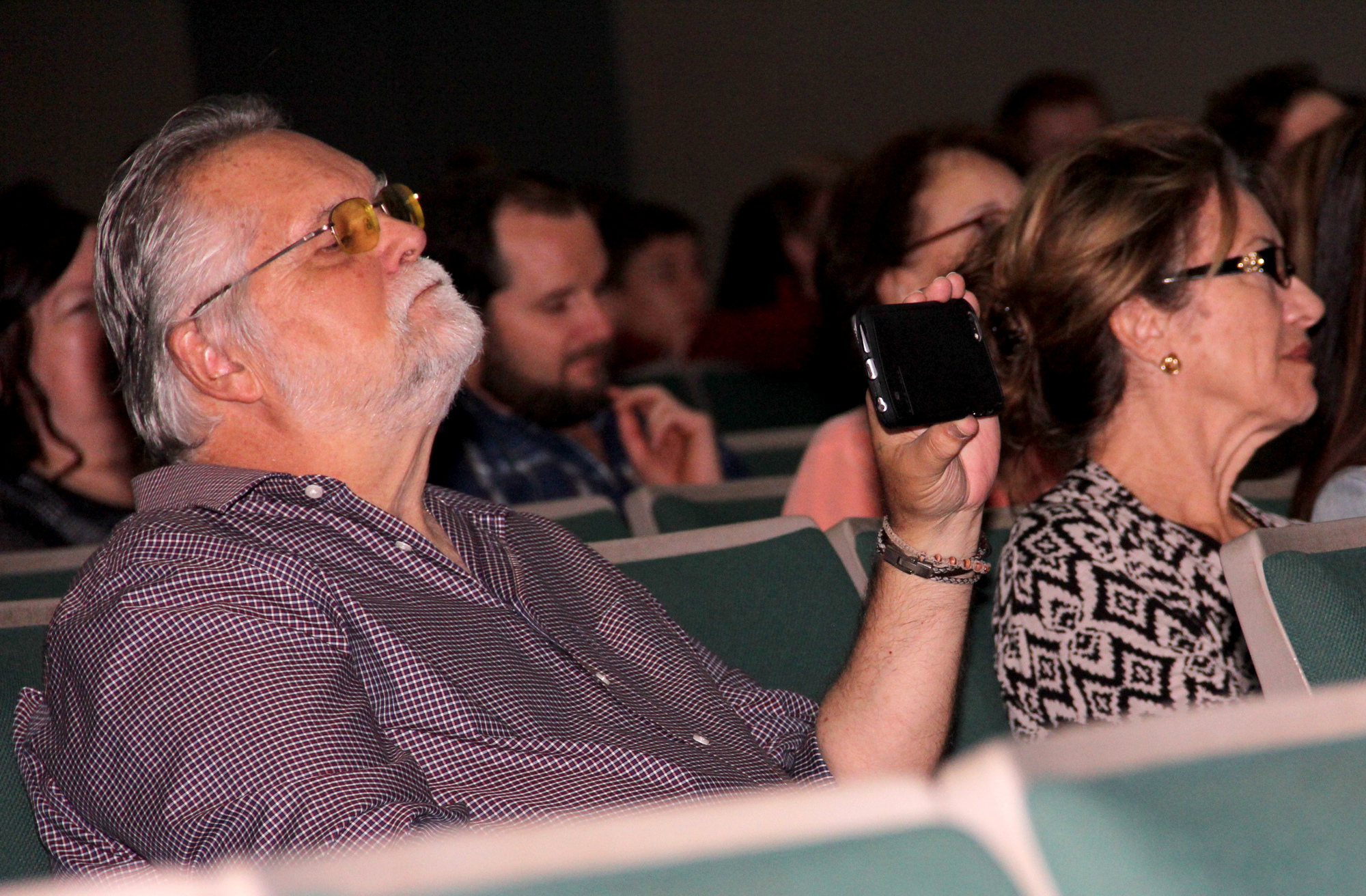 Tony Neste uses his phone to video the Art Hall of Fame inductee program at Flagler Auditorium on Tuesday, March 29. Next to him is Marilyn Neste. The couple's son, A.J.  was one of three FPC graduates being honored. Photo by Jacque Estes
