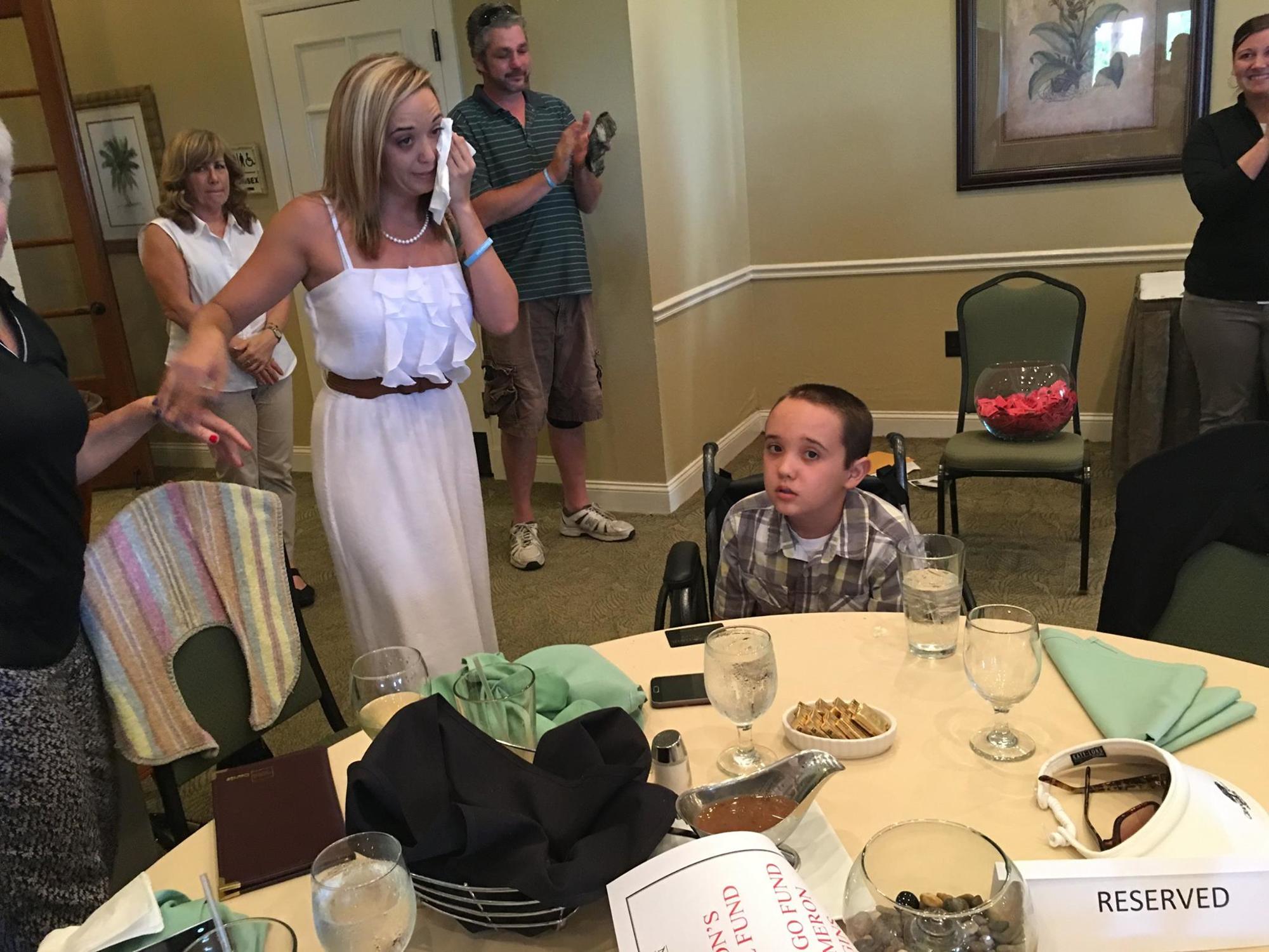 Ashley Higgins wipes away the tears, as Cameron sits by her side, during a fundraising event in his honor at Grand Haven. Courtesy photo