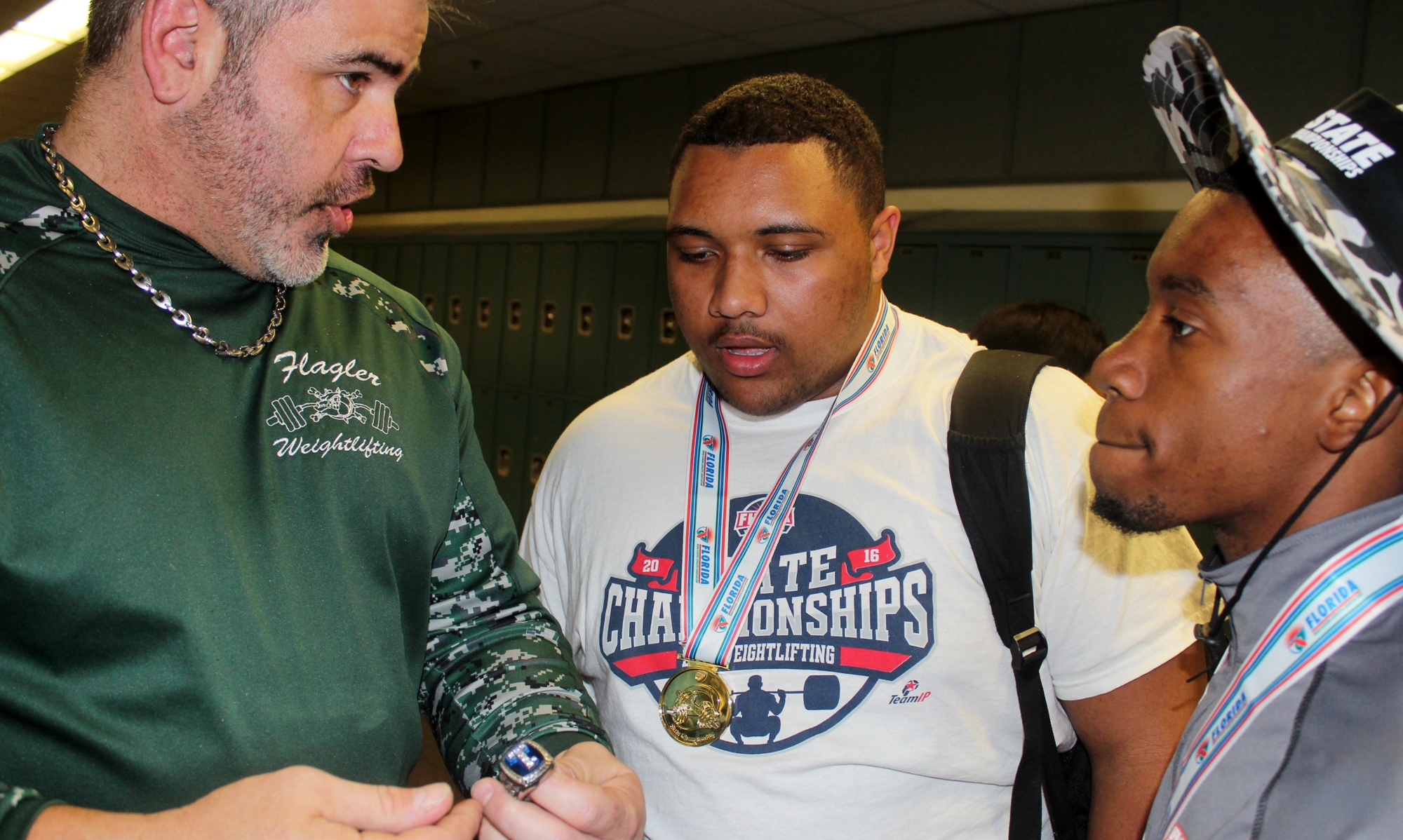 Coach Duane Hagstrom shows his two state champions how their rings will look. Photo by Jeff Dawsey