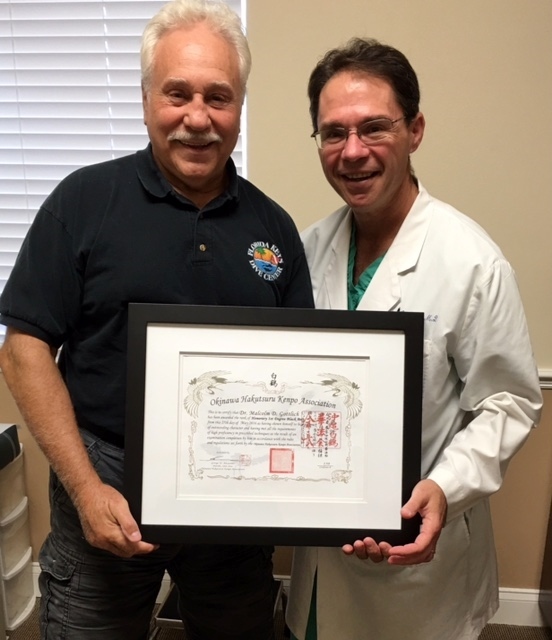 George Alexander presented Dr. Malcolm Gottlich with an honorary black belt for saving his knees. Courtesy photo