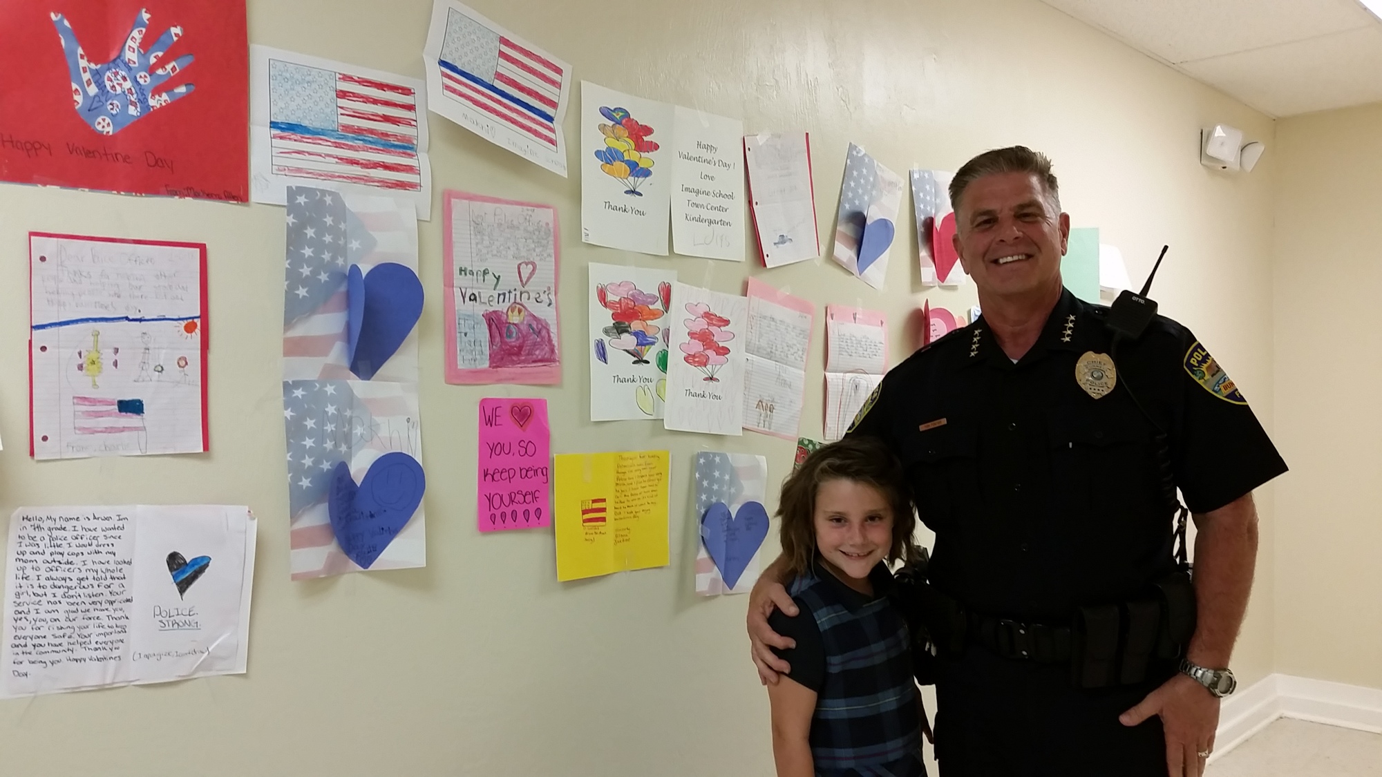 Imagine School student Chloe Bennett and Bunnell Police Chief Tom Foster stand in front of valentines students made. Photo courtesy of Nicole Puritis
