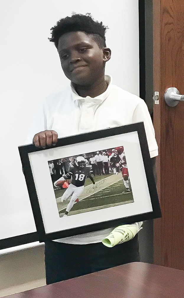 Bunnell Elementary student Faizon Brown, who lost the use of one hand during an accident last year, holds up a signed photo of one-handed linebacker (then UCF) Shaquem Griffin sent to him. Photo courtesy of Angela Reed