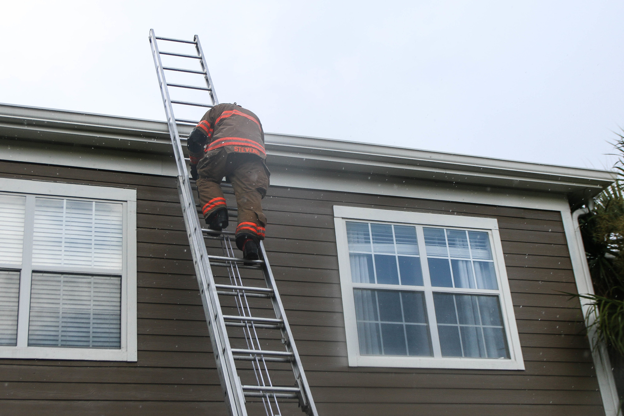 Matt Stevens, of Ladder 25, climbs down a ladder after searching the roof of building 10 for further damages as the rain continues. Photo by Paige Wilson