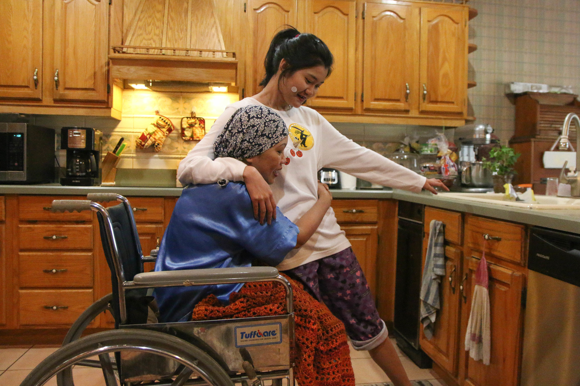 Lexie Peck shares a moment with her youngest daughter, Chelsea Ramirez, in the kitchen. Photo by Paige Wilson