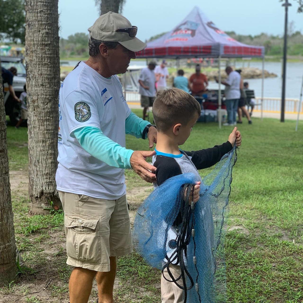 Volunteer Bear Carter shows a young angler how to throw a cast net. Photo courtesy of Marketing2Go