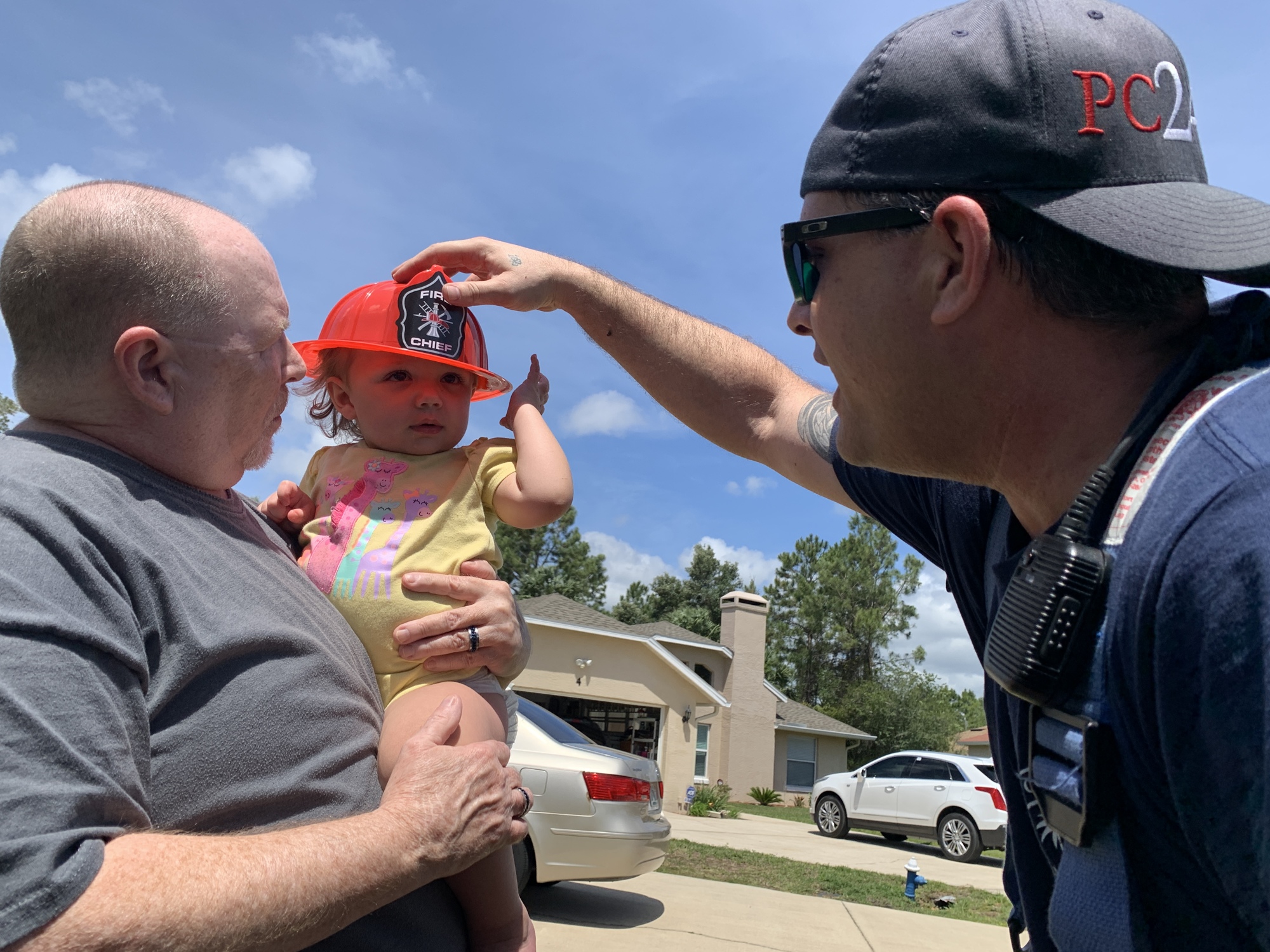 Driver Engineer Travis Greco puts a souvenir hat on the youngest Kling, 1-year-old Trinity. Trinity is held by Neil Crawford, adoptive dad of Shawn and Gordon.