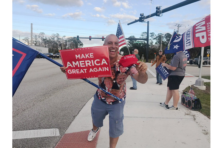 Chris Feeney holds a MAGA sign in a counter protest on S.R. 100 in January. Photo by Paola Rodriguez