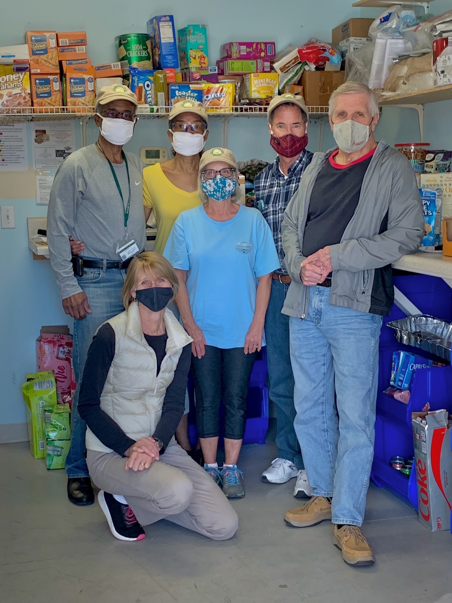 Michele Seyfert (kneeling) at Our Father's Table's storage facility with volunteers (from left) Marvin Ellison, Adrienne Ellison, Sandra Strickland, Gerald Strickland and Charlie Seyfert. Photo by Jonathan Simmons