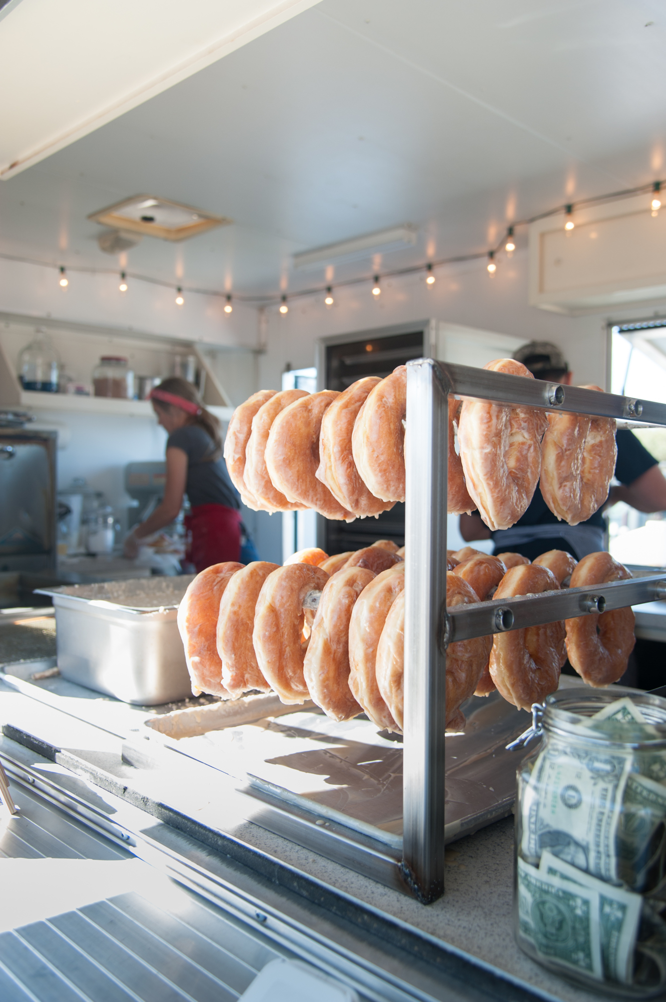 Doughnuts hang on a rack while the glaze settles.