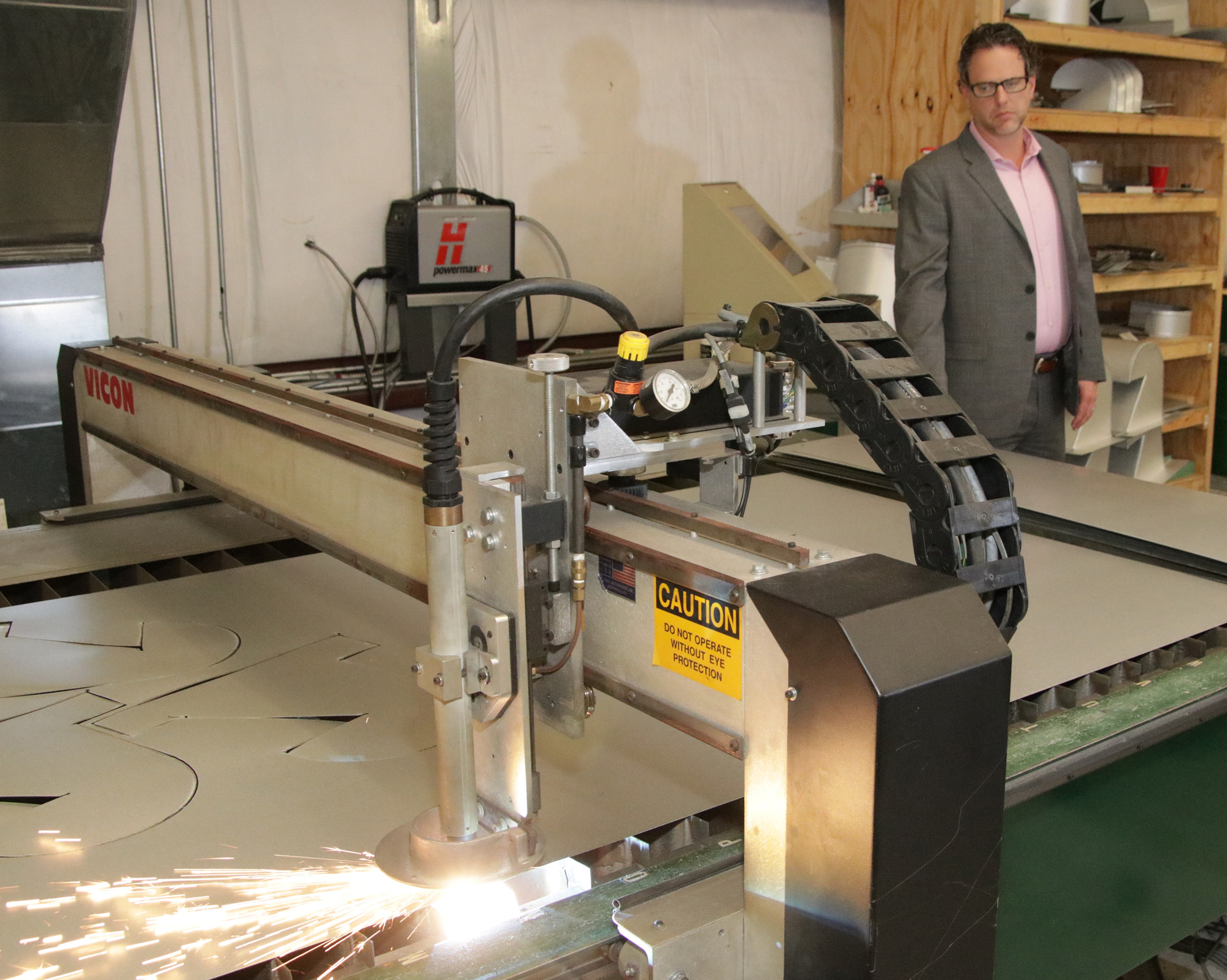 Jeff  Bonk watches his favorite piece of equipment, the plasma cutter, shape pieces from a sheet of metal.