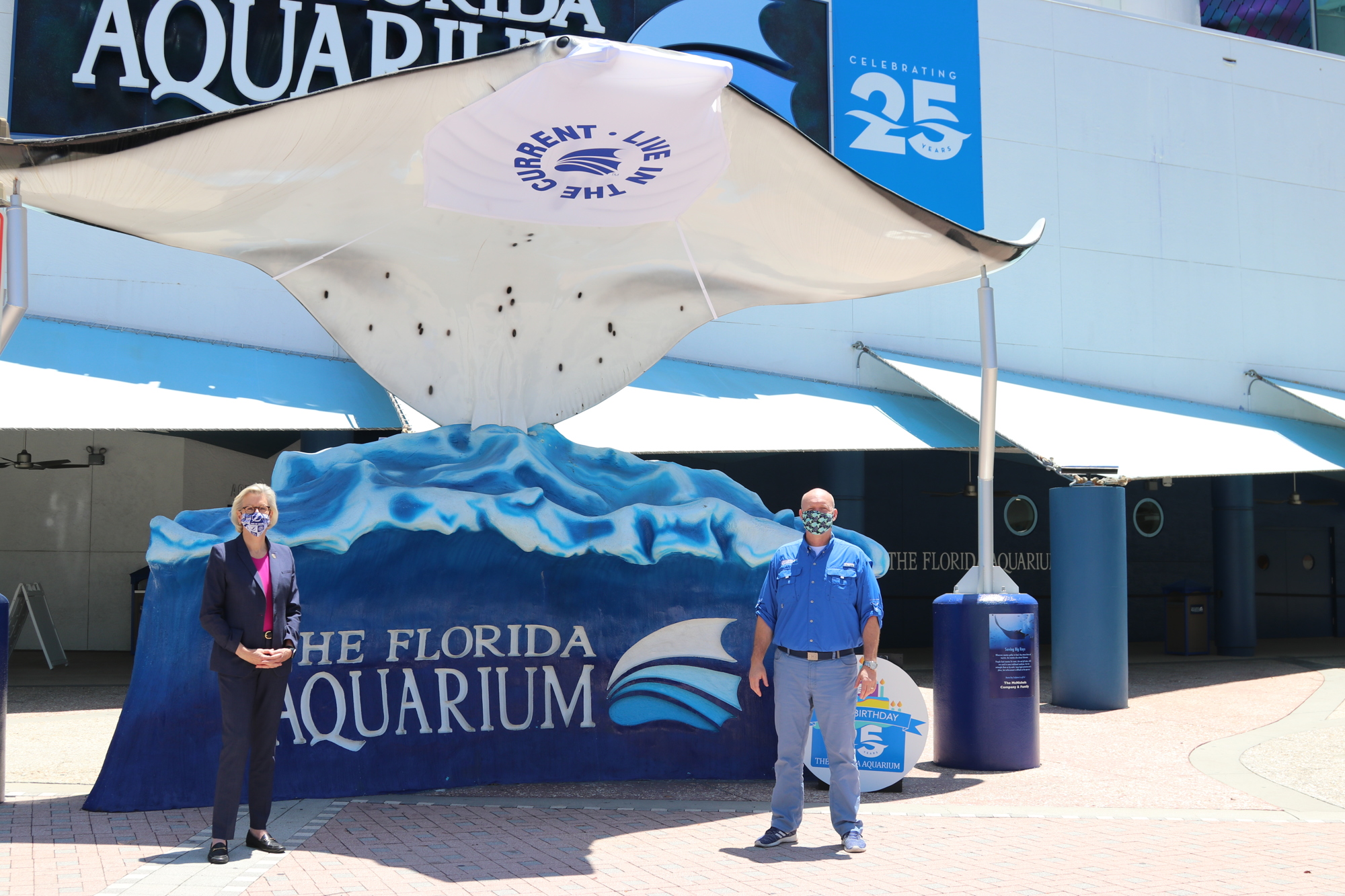 Courtesy. Tampa Mayor Jane Castor and Florida Aquarium CEO Roger Germann wearing face masks, along with the aquarium's giant manta ray statue.