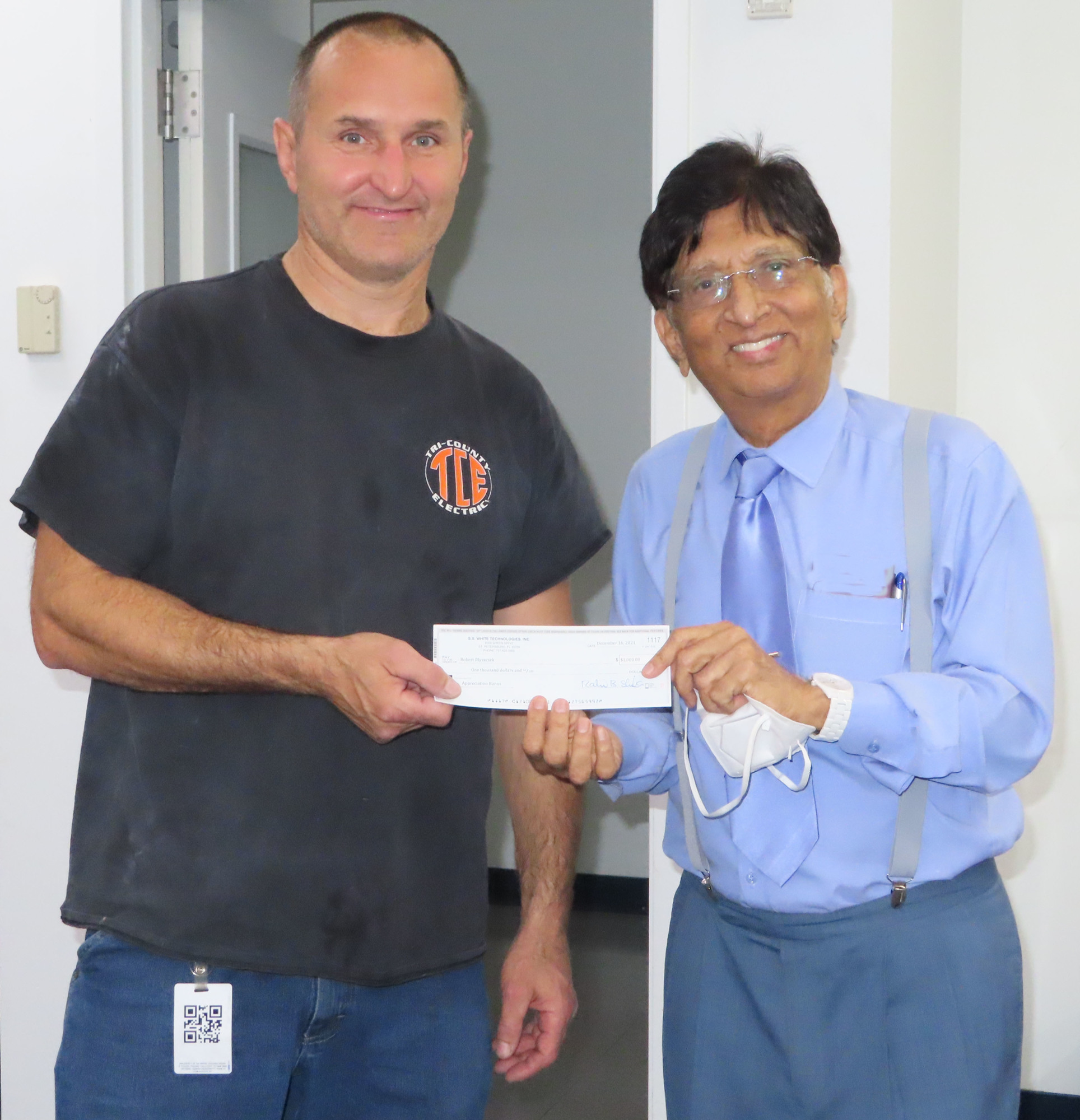 Courtesy. S.S. White Technologies and Shukla Medical owner and CEO Rahul Shukla, left, gives a $1,000 holiday bonus check to staff member Robert Blyszczek.