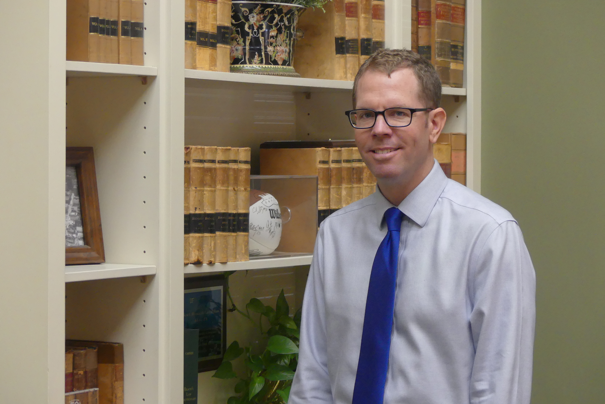 Brian Coughlin in the law library in at the Bedell Firm, which features a Jaguars autographed football.