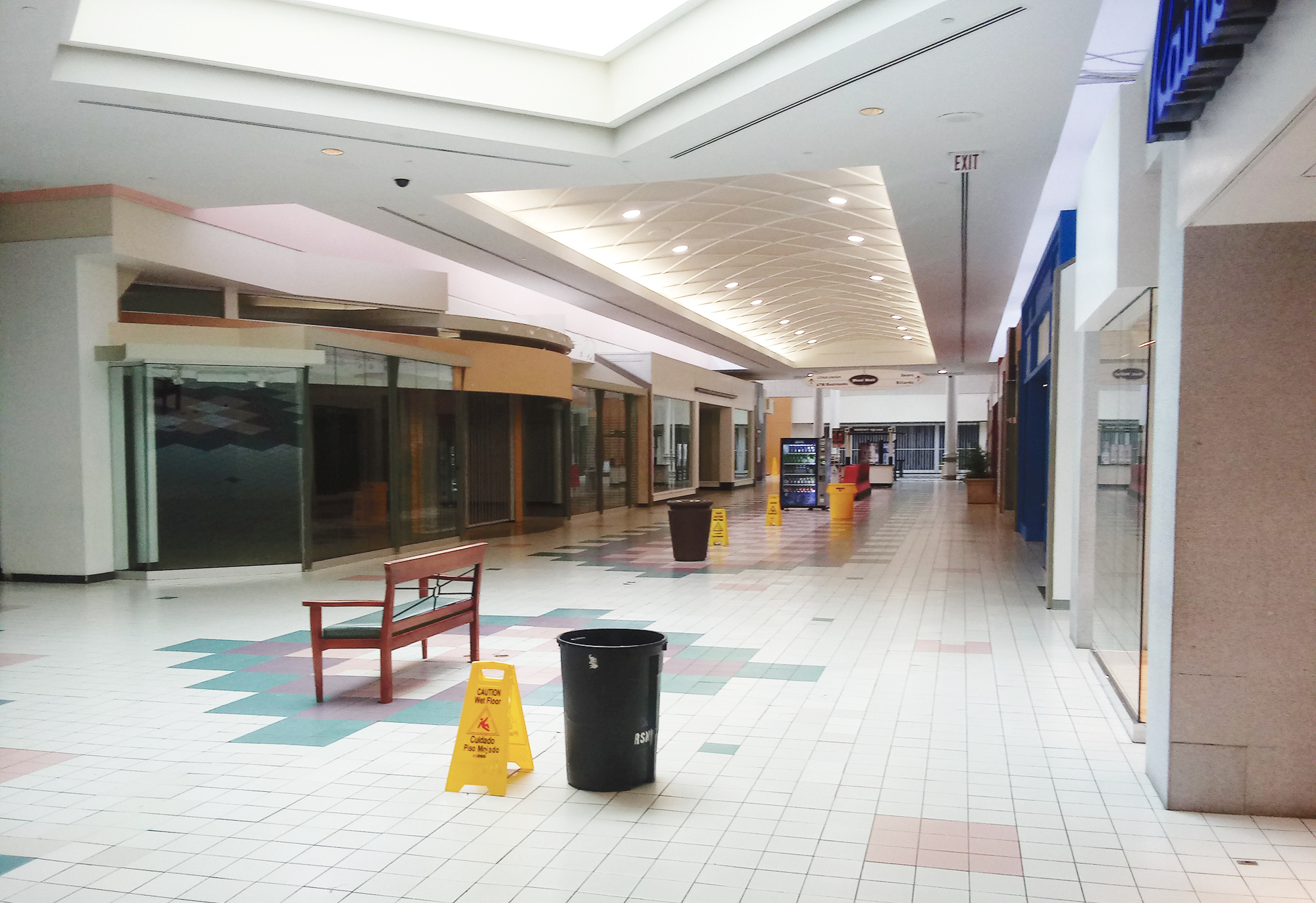 Trash cans placed in walkways to catch water leaking through the roof and “wet floor” warning signs stand in a nearly empty wing of Regency Square.