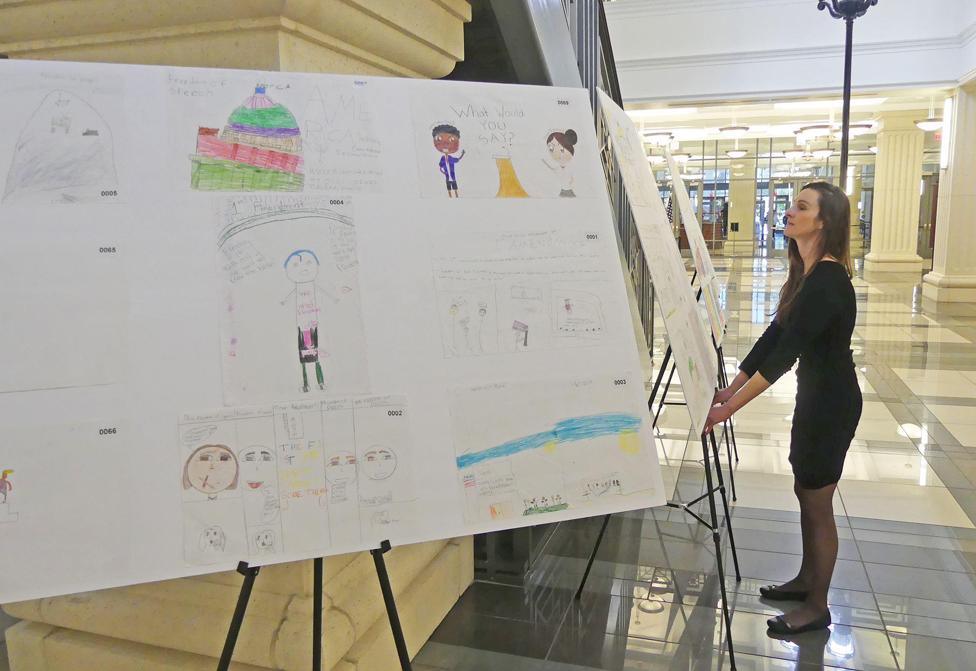 Law Week Committee Chair Kelli Lueckert places posters created by West Riverside Elementary School students at the Duval County Courthouse.