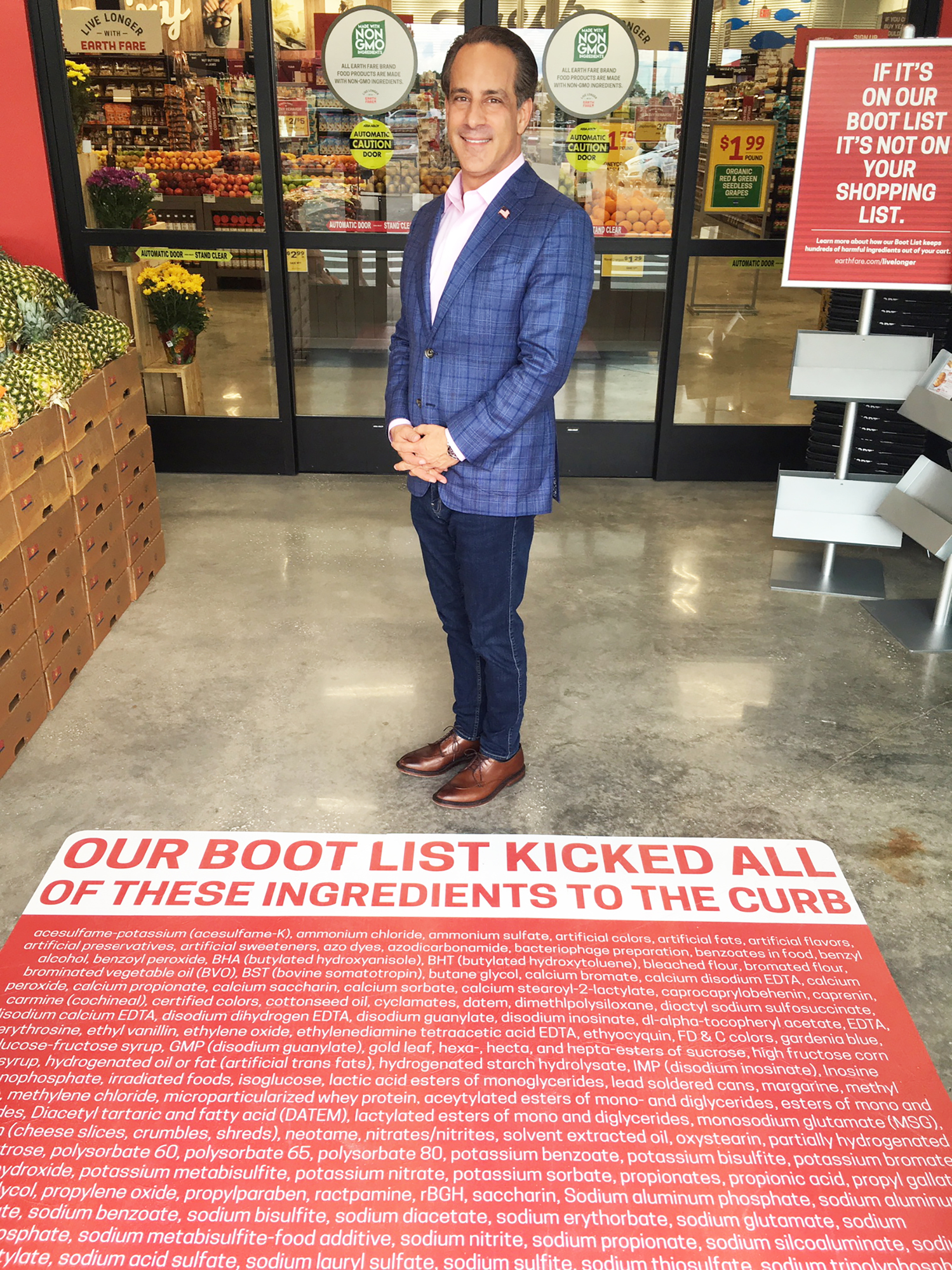 Frank Scorpiniti, Earth Fare president and CEO, stands in front of the Boot List that greets customers at the front door.