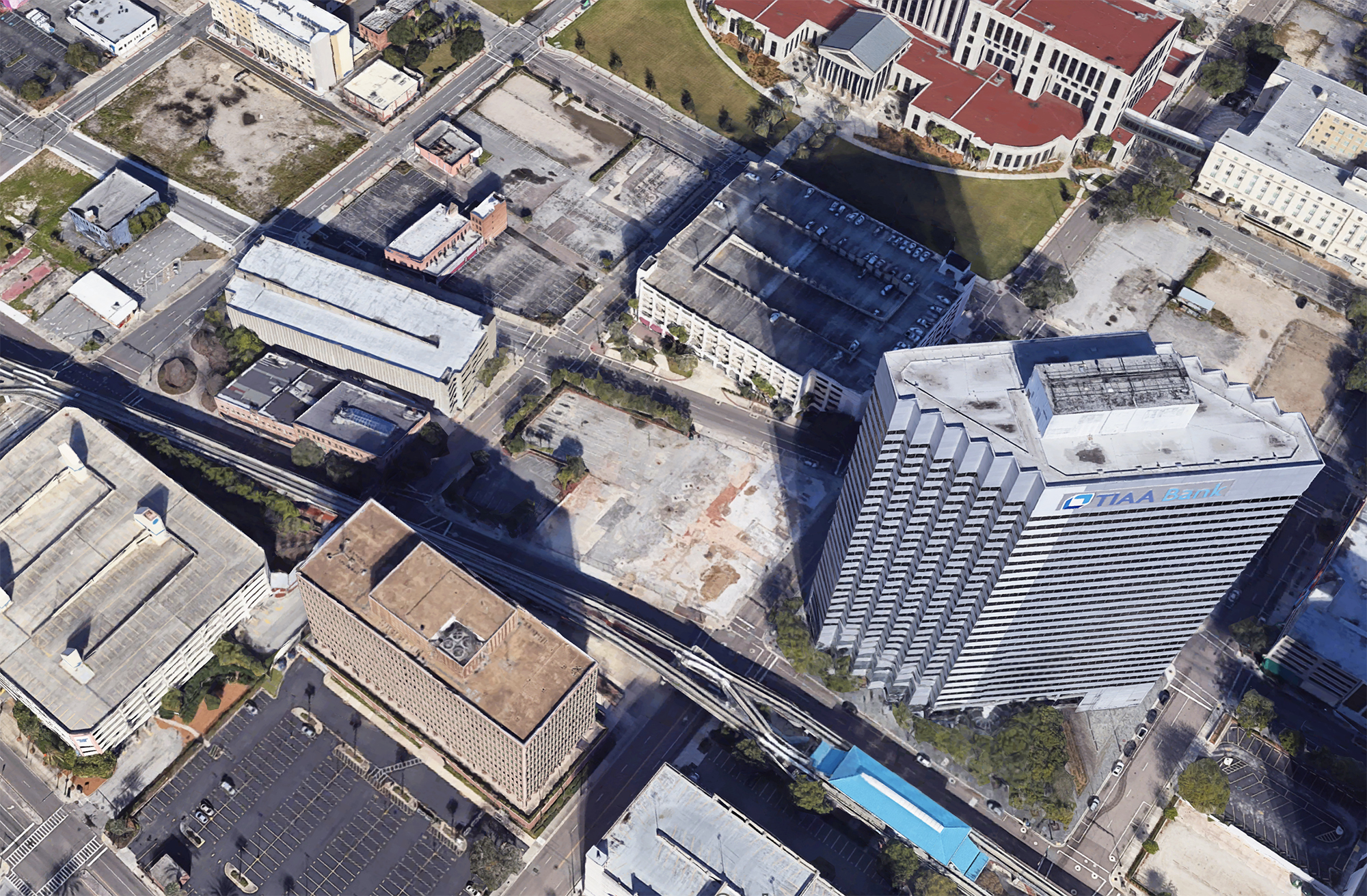 A Google satellite image shows a vacant lot at 10 N. Pearl St. near the TIAA Bank Center where Greyhound previously had a station. The station was demolished and the area is now a parking lot. A 54-story building could rise there.