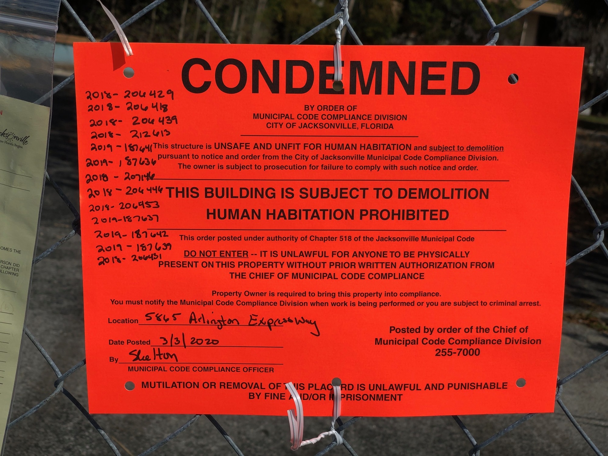 “This structure is unsafe and unfit for human habitation and subject to demolition,” says an orange “condemned” sign dated March 3 on the fence at 5865 Arlington Expressway.