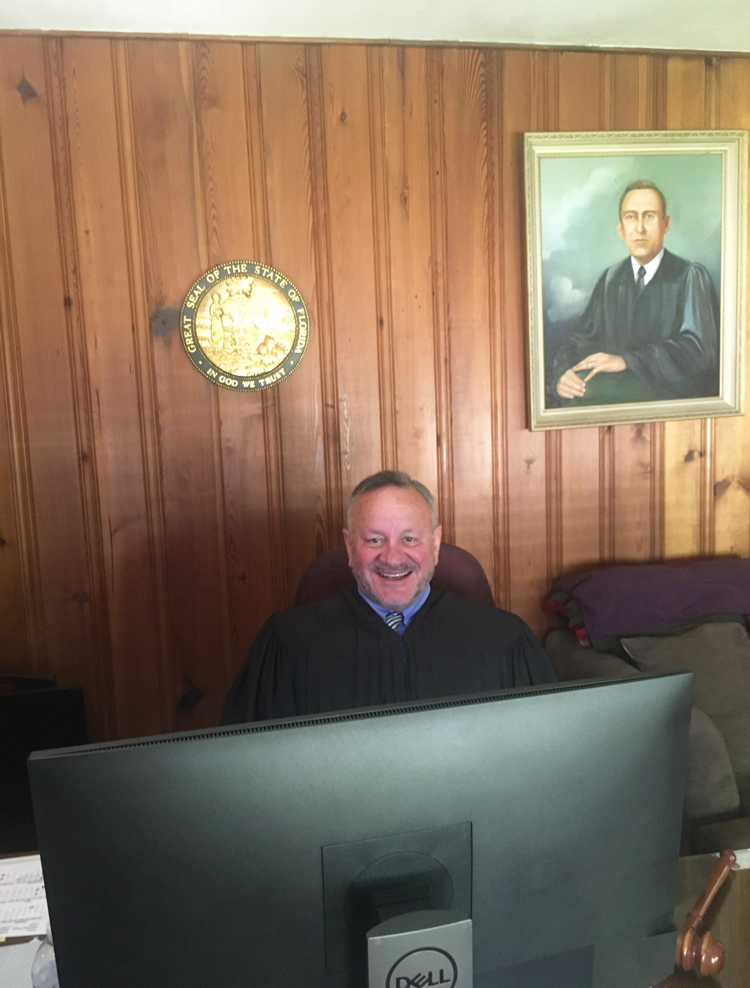 Circuit Judge David Gooding works in his home den. A portrait of his late father, Circuit Judge Marion Gooding, looks over his shoulder as he presides over adoption proceedings and juvenile hearings.