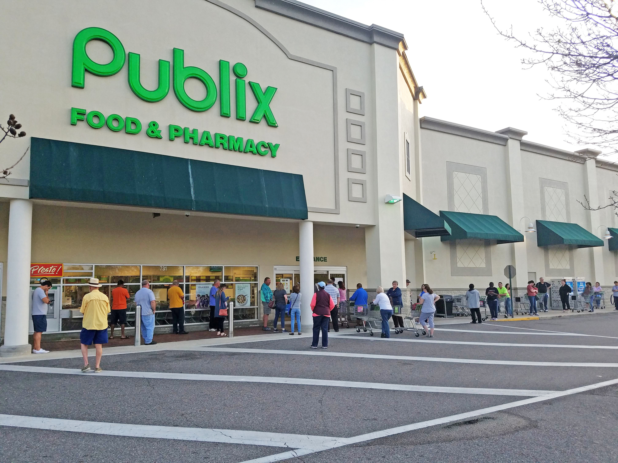 People line up to shop at Publix, which reduced hours because of COVID-19.