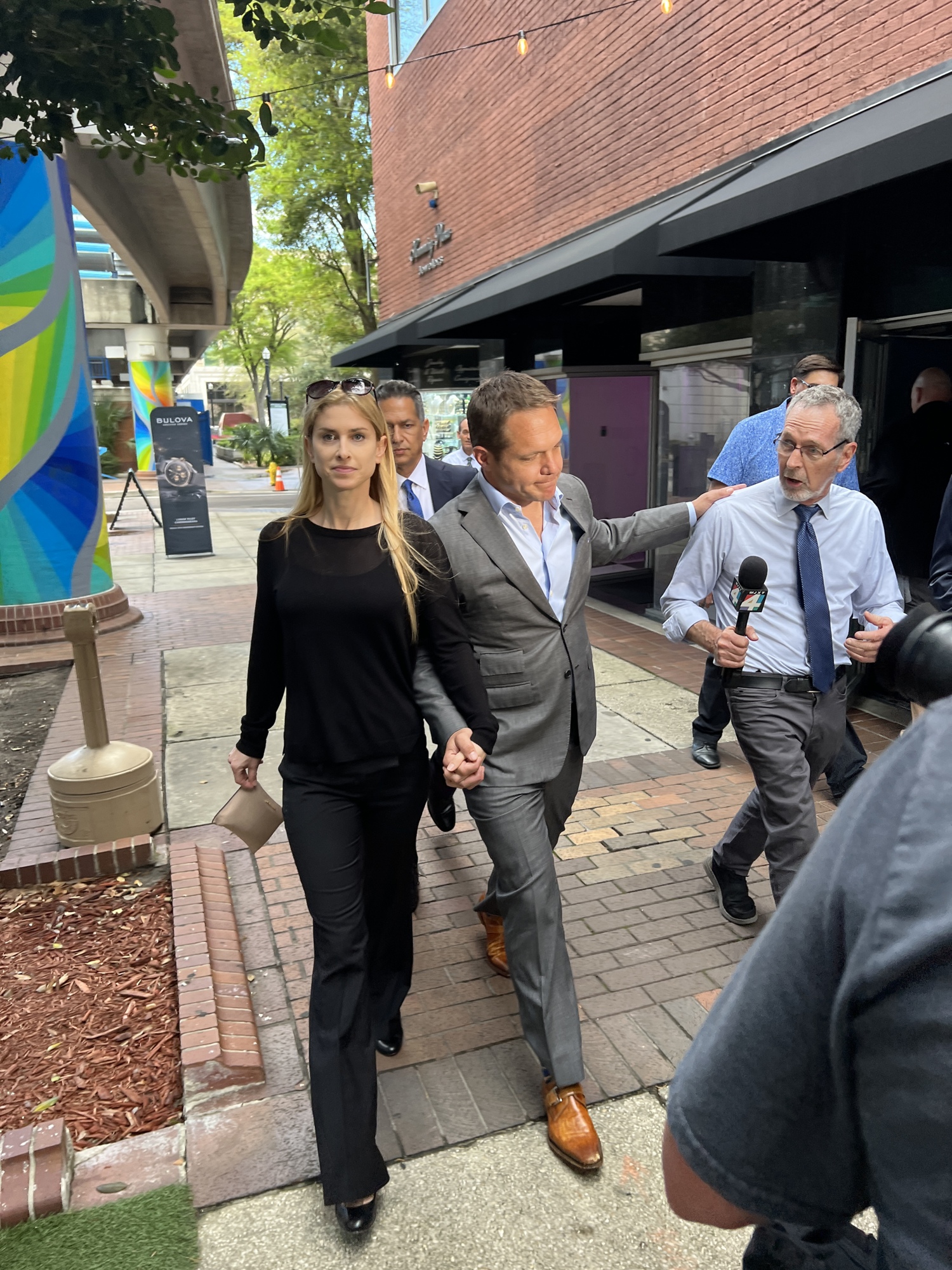 Fired JEA CEO Aaron Zahn puts his hand on the shoulder of WJXT Channel 4 reporter Jim Piggott March 8 after leaving the federal courthouse where he pleaded not guilty to federal charges.