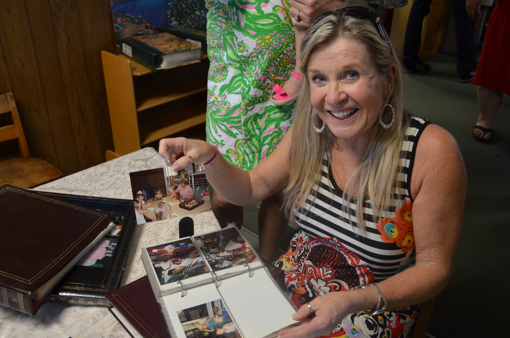 Jacki Hamilton Kleppinger searches through photo 30 years worth of photo albums looking for photos of her daughters and son who attended Swiss Day Preschool.