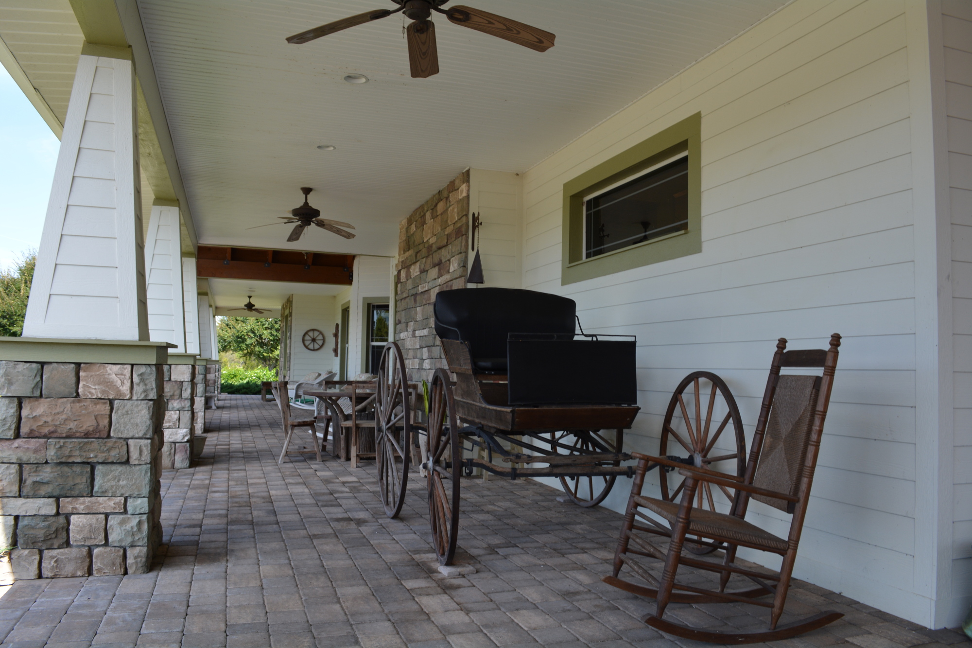 The main home includes a pavered wrap-around porch, currently decorated with rocking chairs, an old horse buggy and other decor.