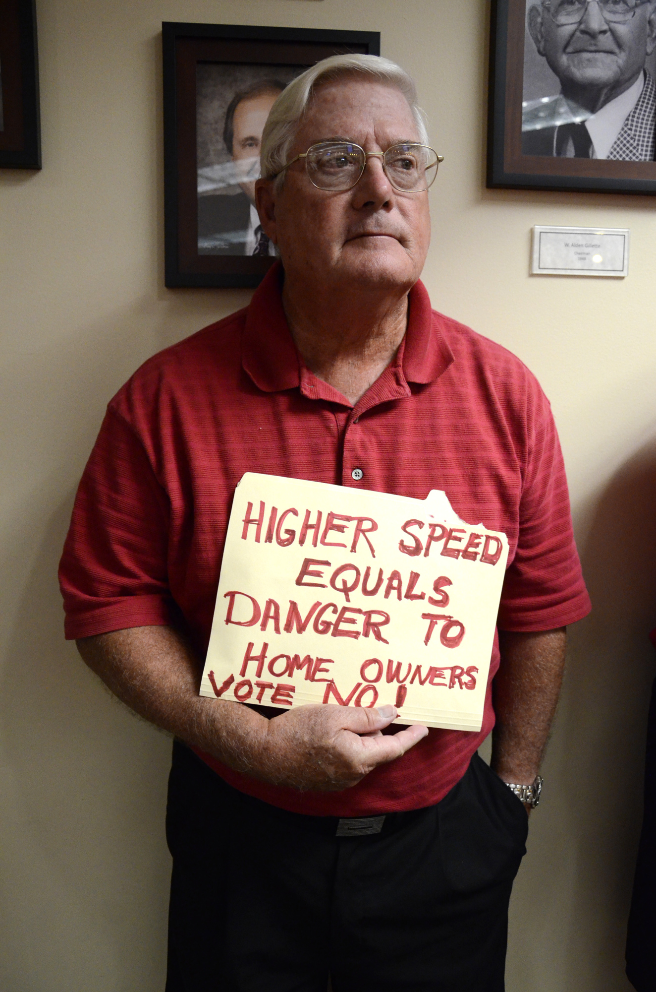 Don Betts stands in the back of the Manatee County Commission Chambers with a sign reading 