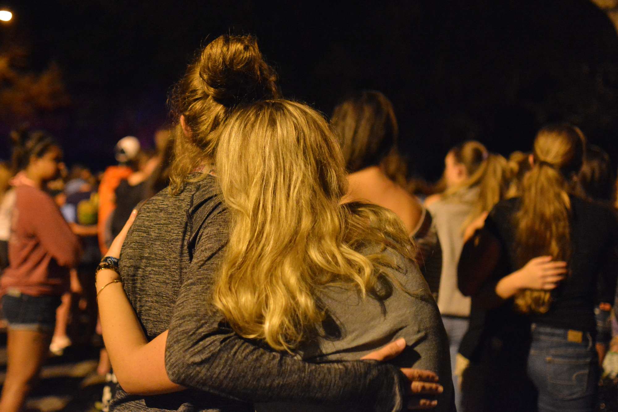 Lucy Milbourn and Ali Alger share an embrace as they stand at the candlelight vigil.