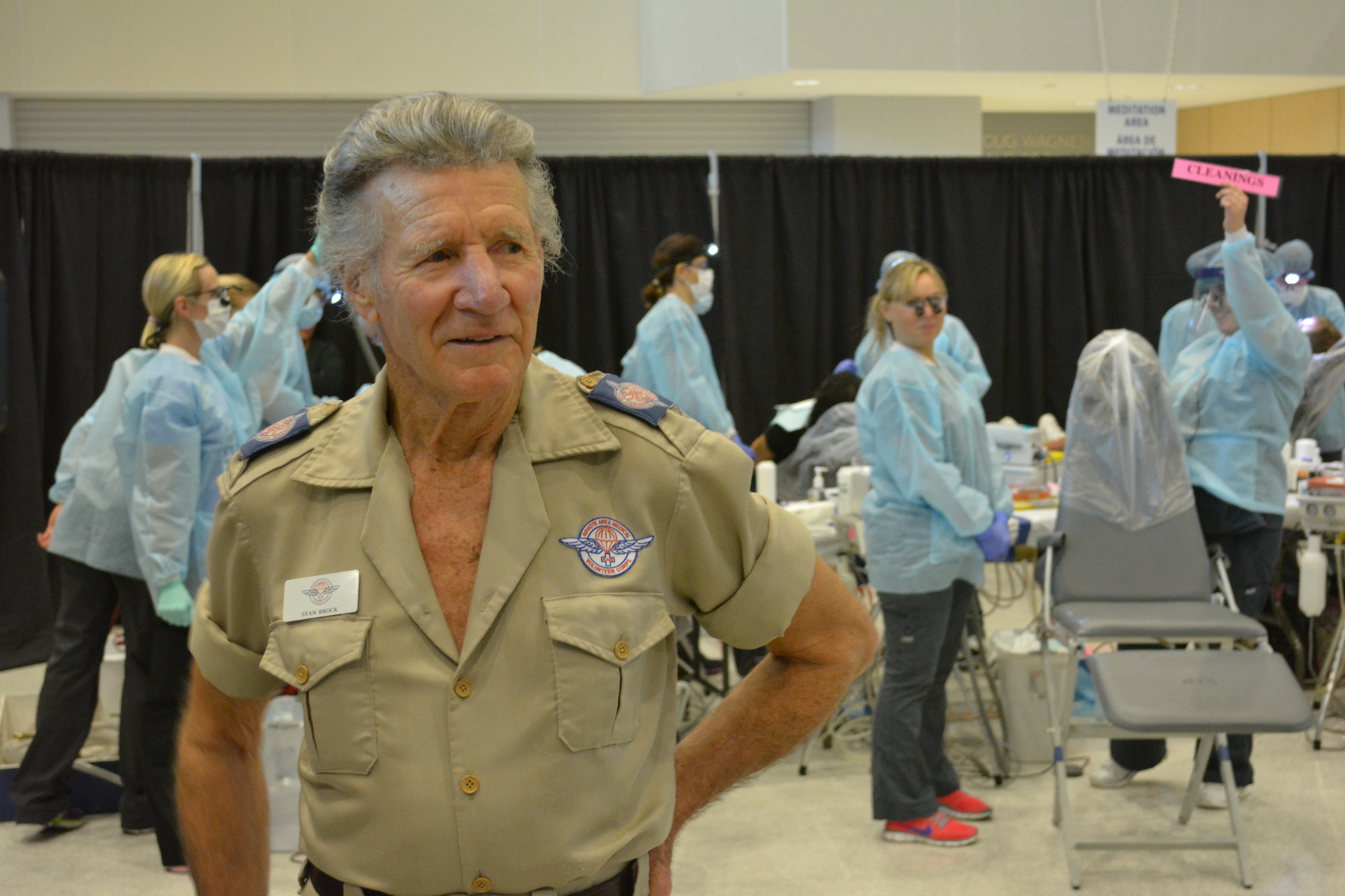 Stan Brock, founder of Remote Area Medical, tours the floor of Manatee Technical College in Bradenton on Saturday as patients in the background receive dental care.